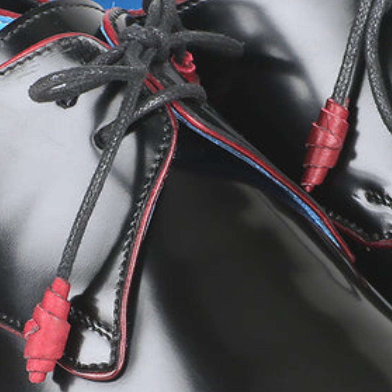 Close-up of black shoes with red accents and laces on a dark background