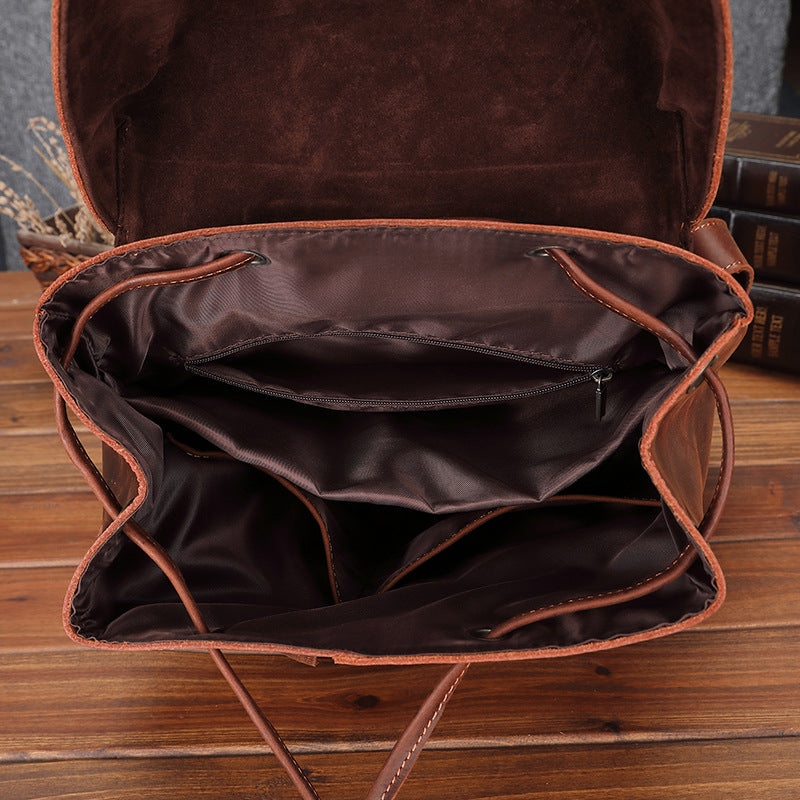 Brown leather bag with open interior on a wooden surface