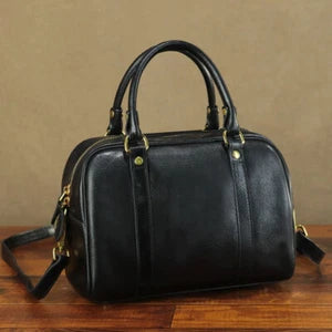 Black leather handbag on a wooden surface with a brown background