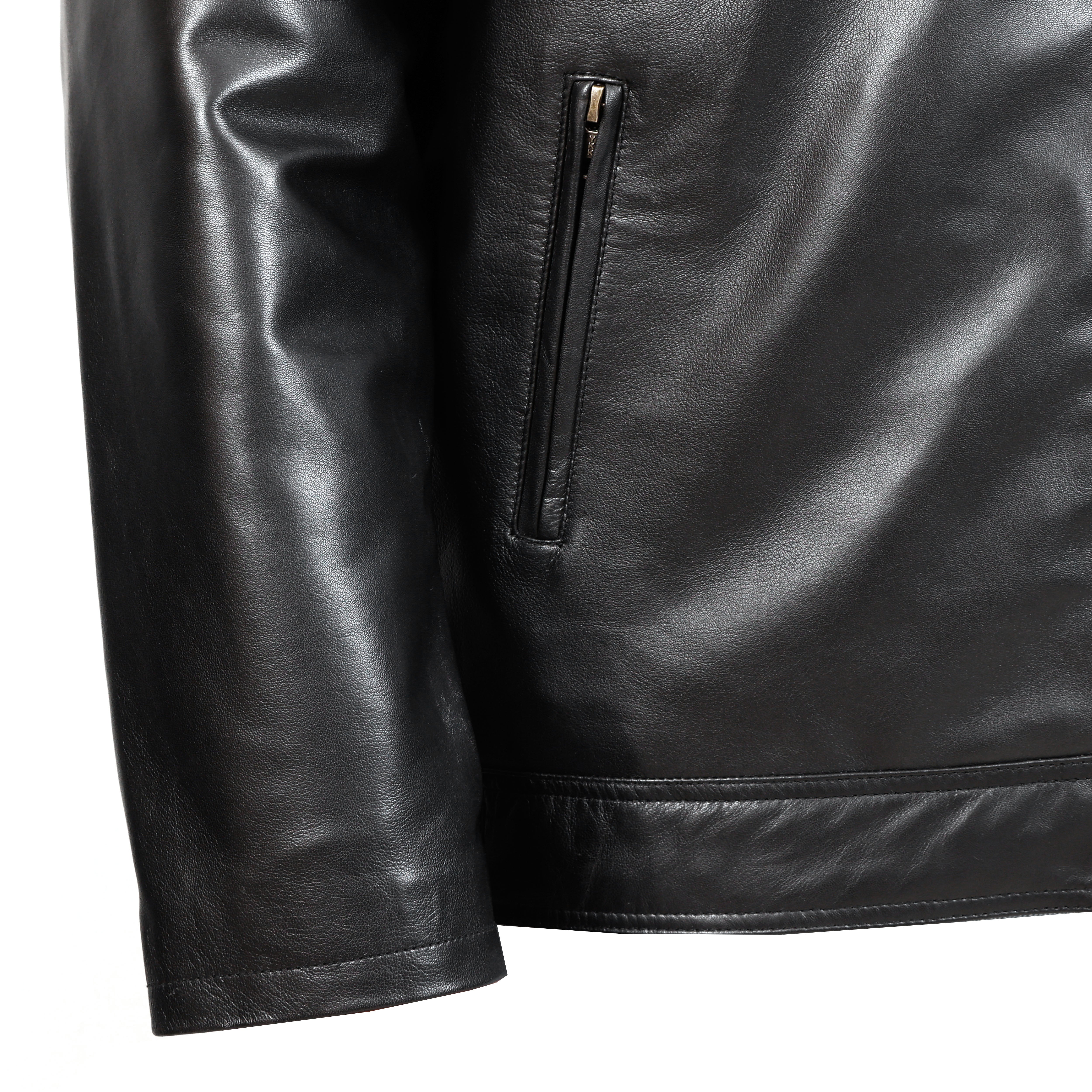 Close-up of a black leather jacket with a zipper detail on a white background