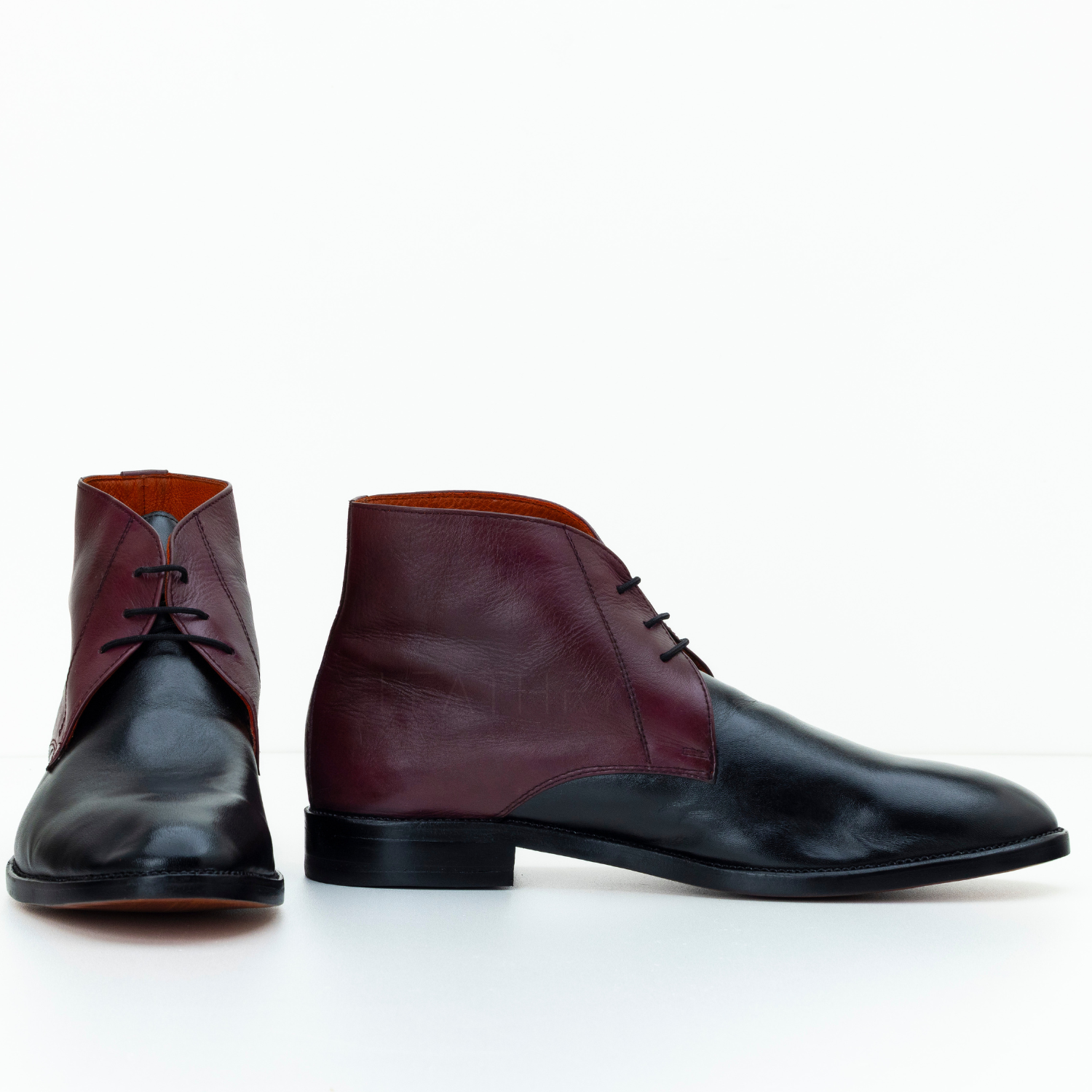 Pair of maroon and black leather shoes on a white background