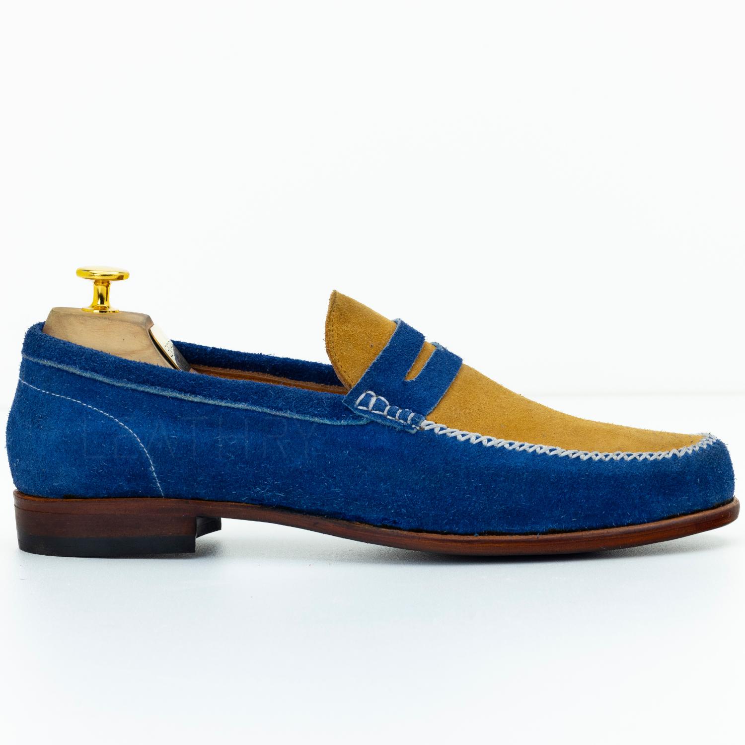 Blue suede loafer with brown sole on a white background