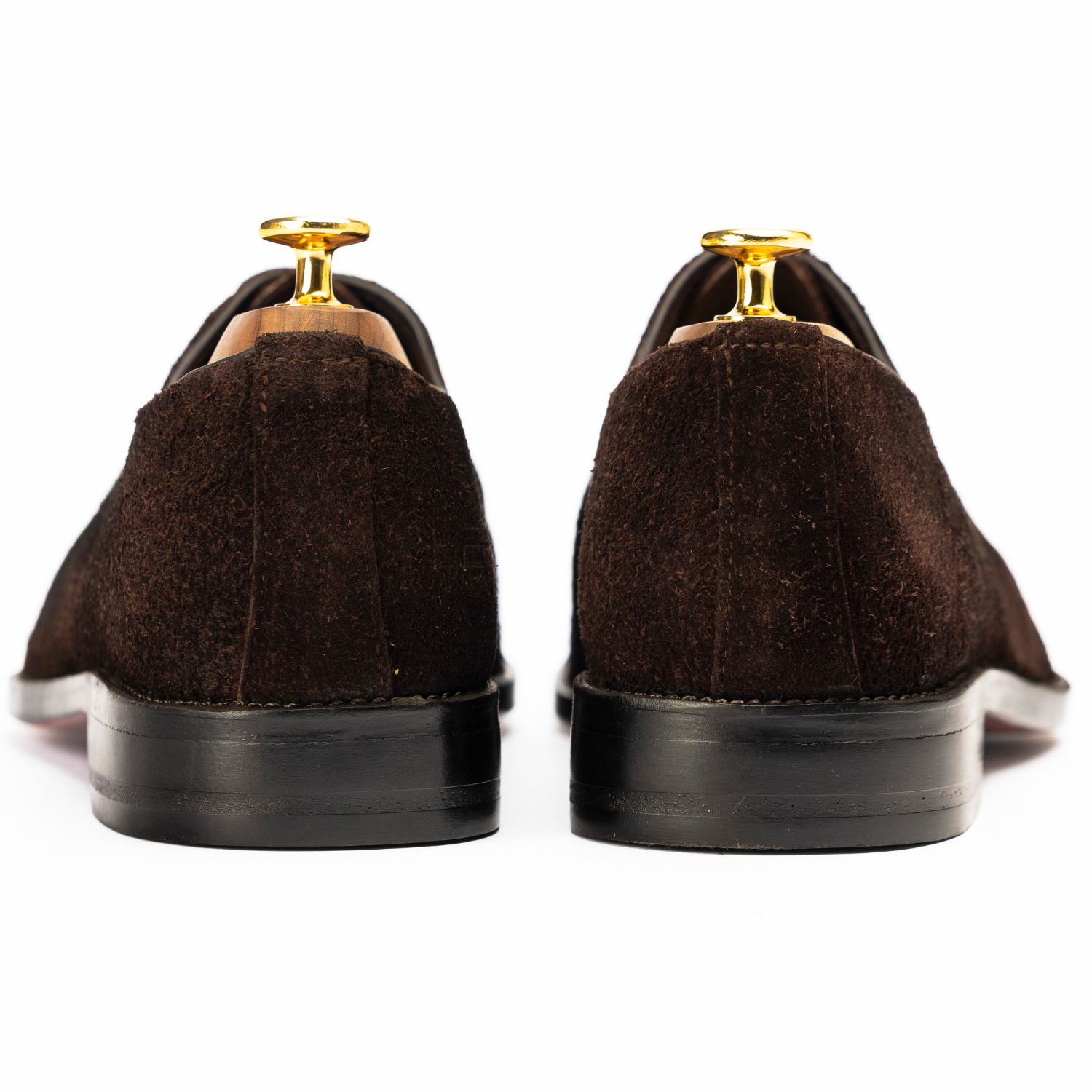 Brown suede shoes with gold accents on a white background