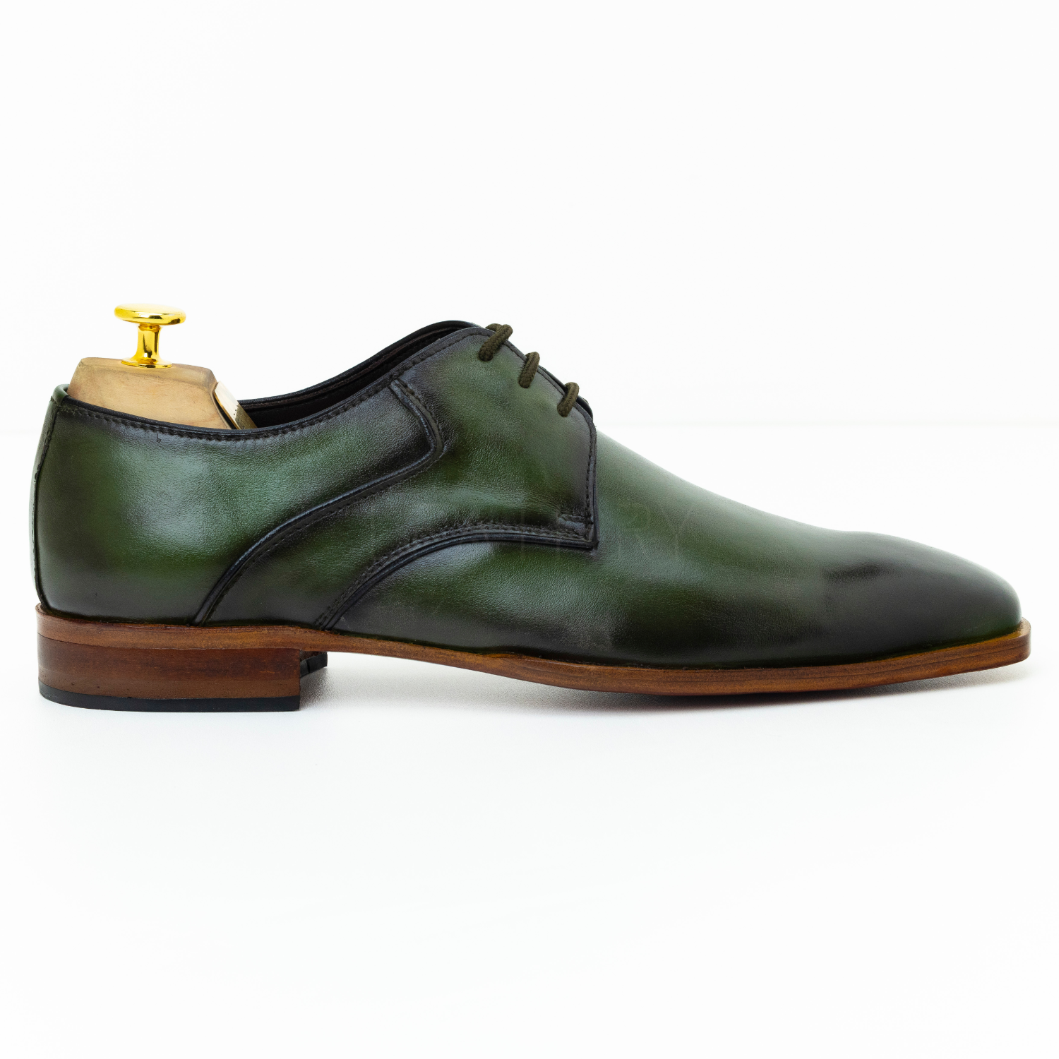 Green leather dress shoe with brown sole on a white background