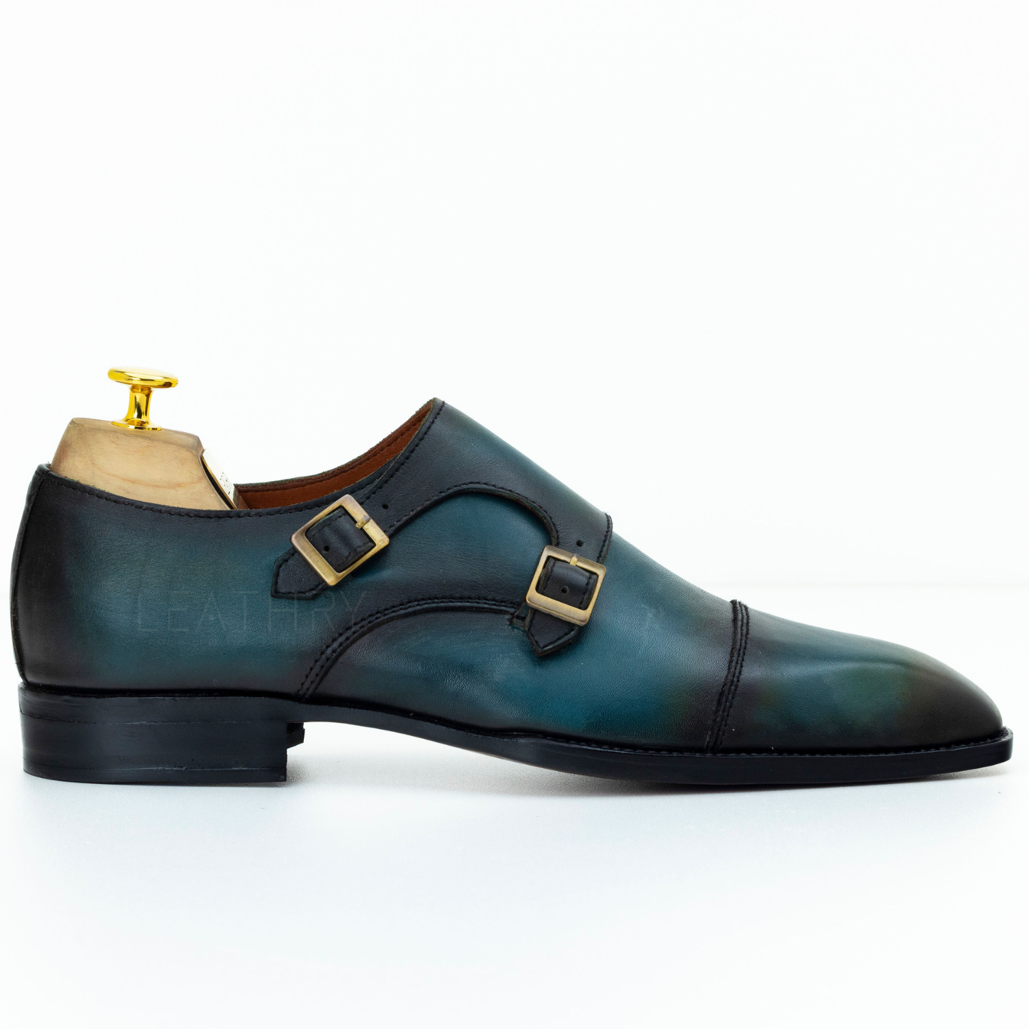 Green leather shoe with gold buckles on a white background