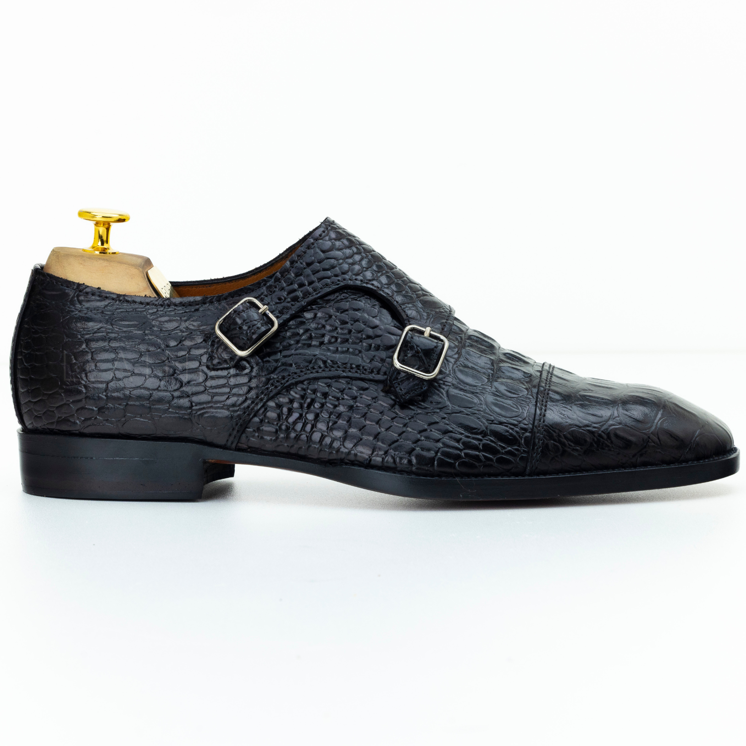 Black textured leather shoe with two buckles on a white background