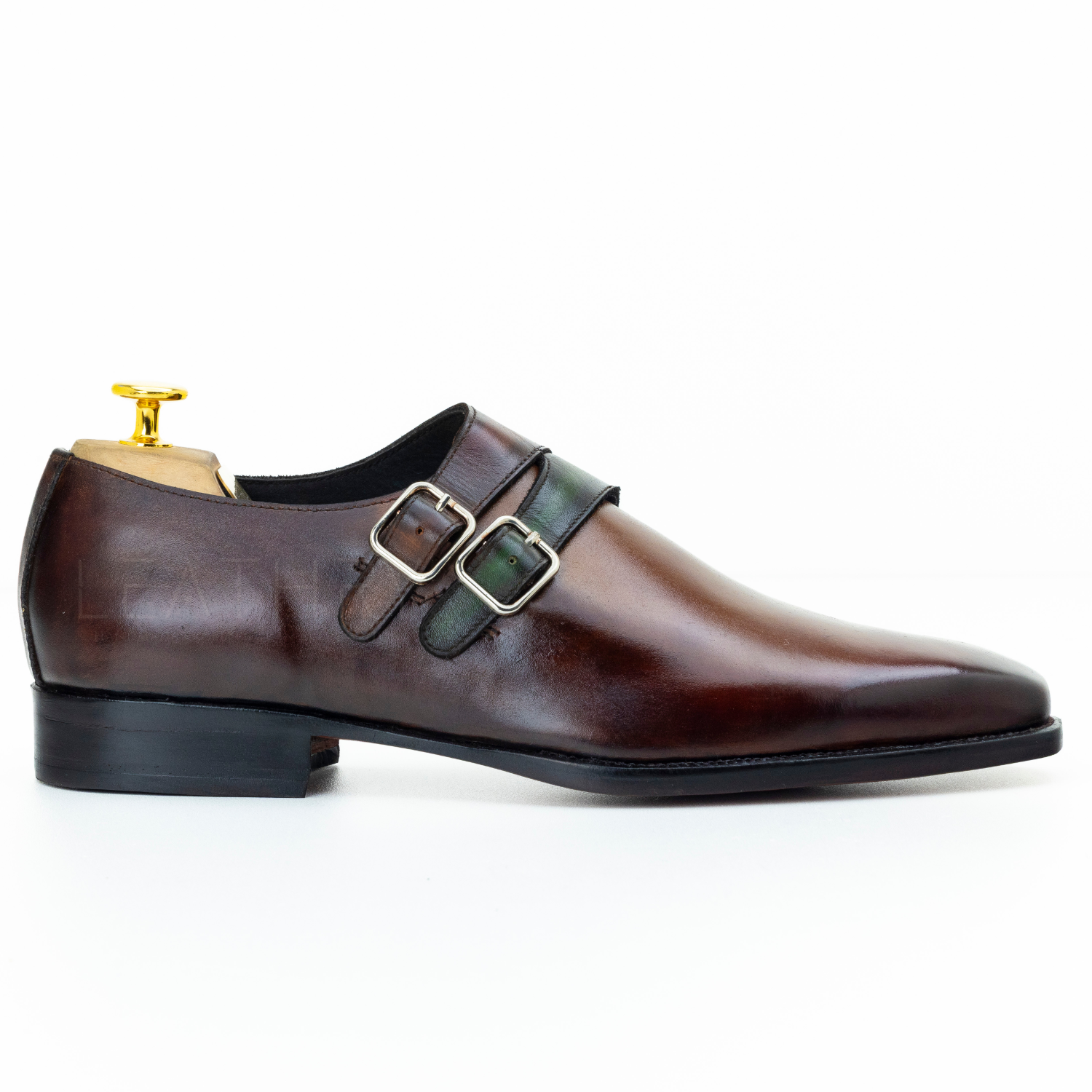 Brown leather shoe with gold buckles on a white background