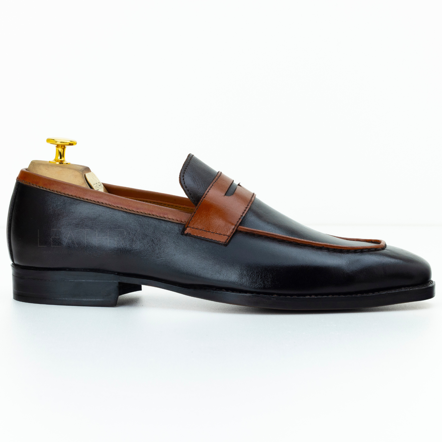 Black leather loafer with brown accent on a white background