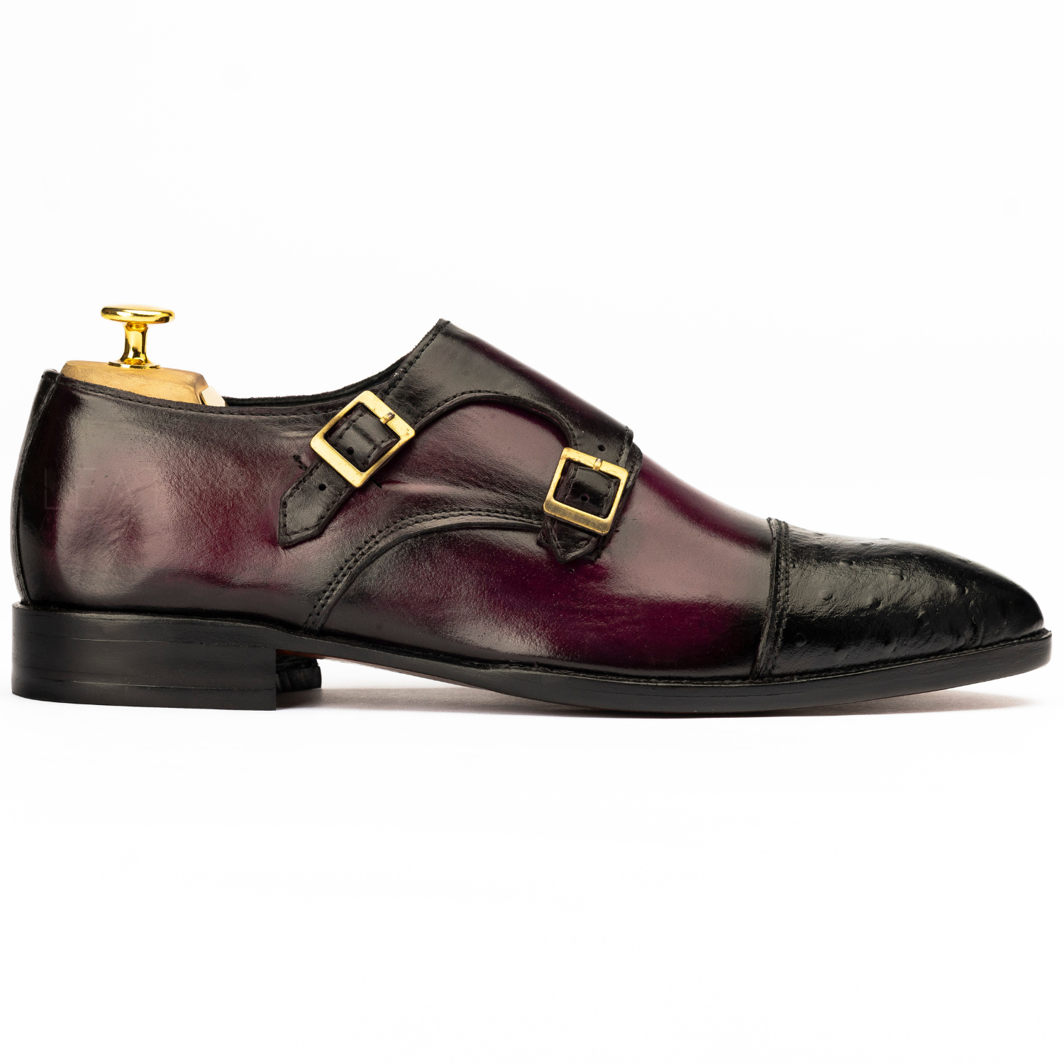 Burgundy leather shoe with gold buckles on a white background