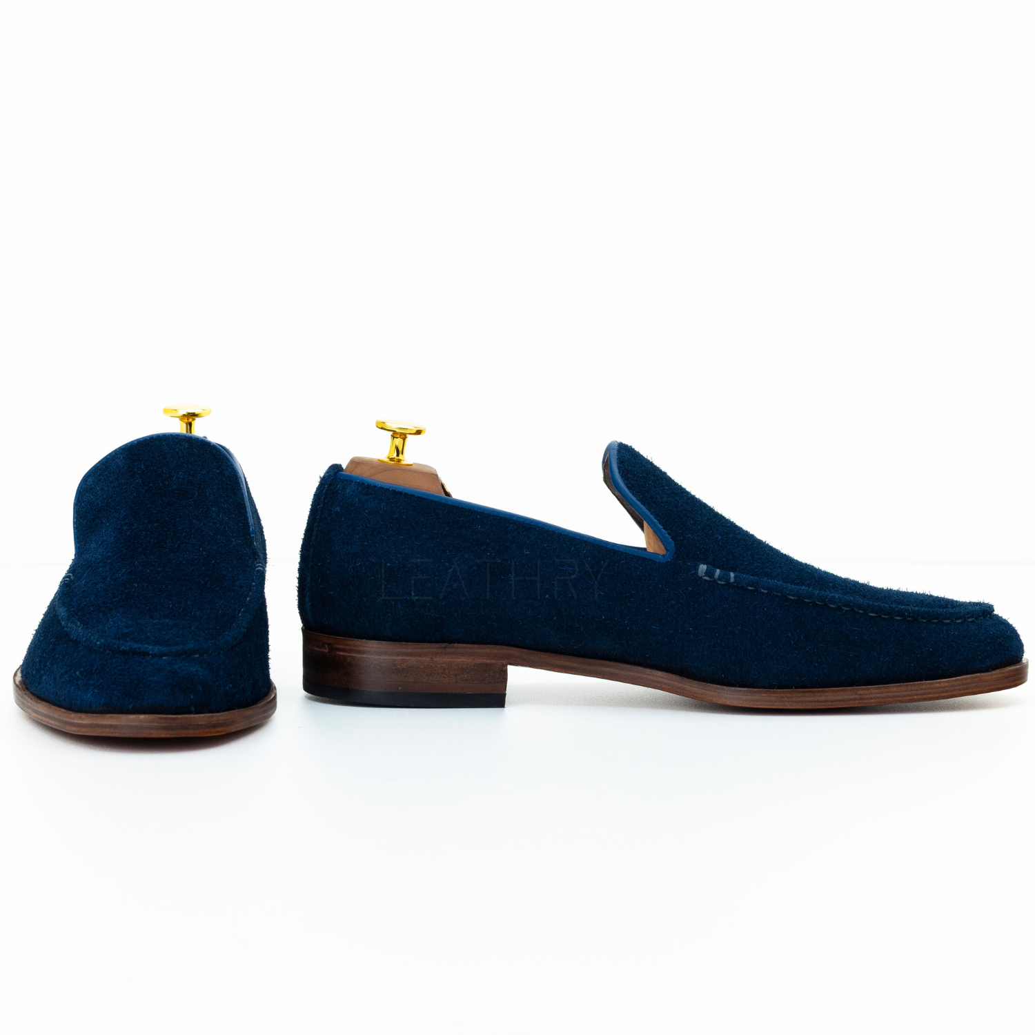 Pair of navy blue loafers with brown soles on a white background