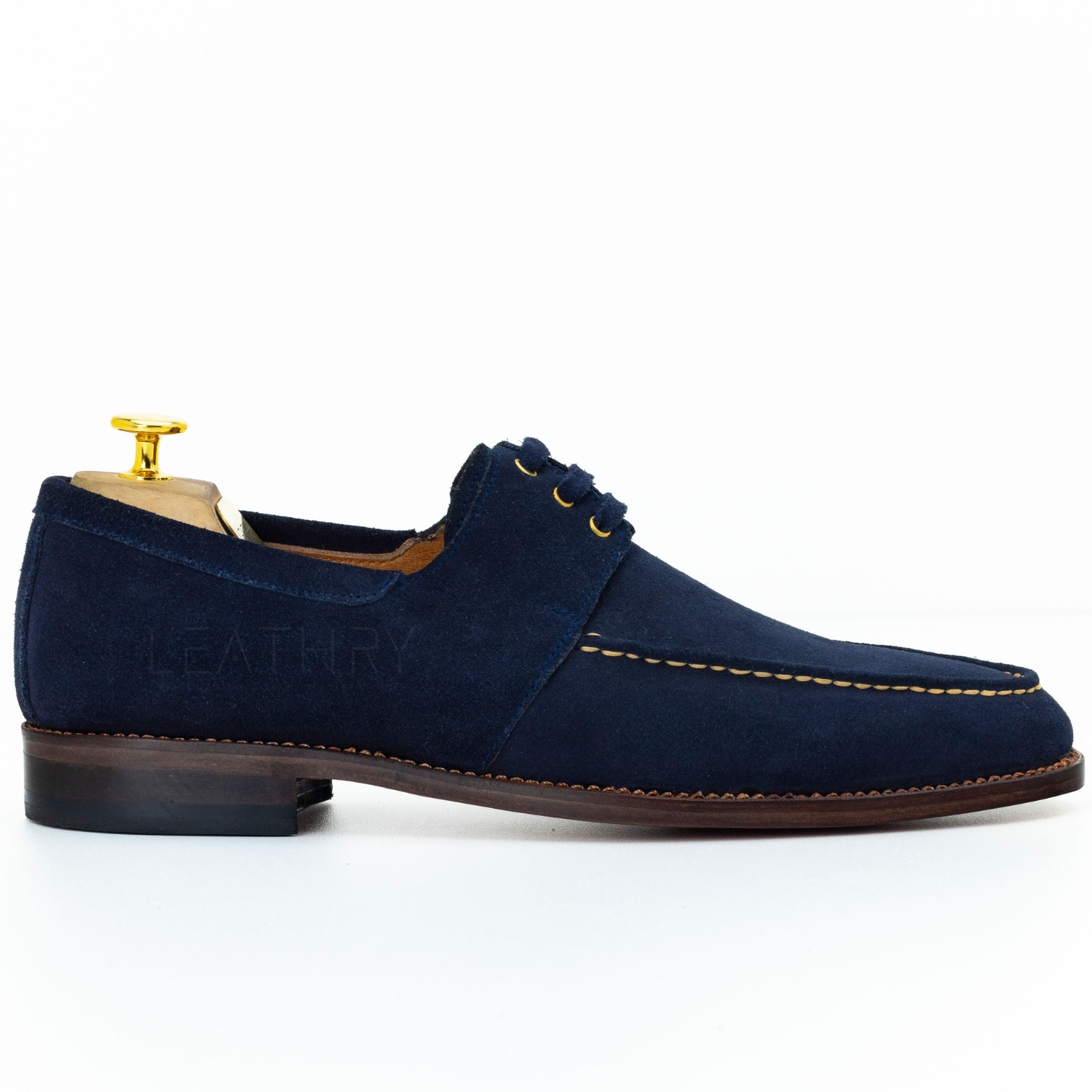Navy blue suede shoe with gold accents on a white background
