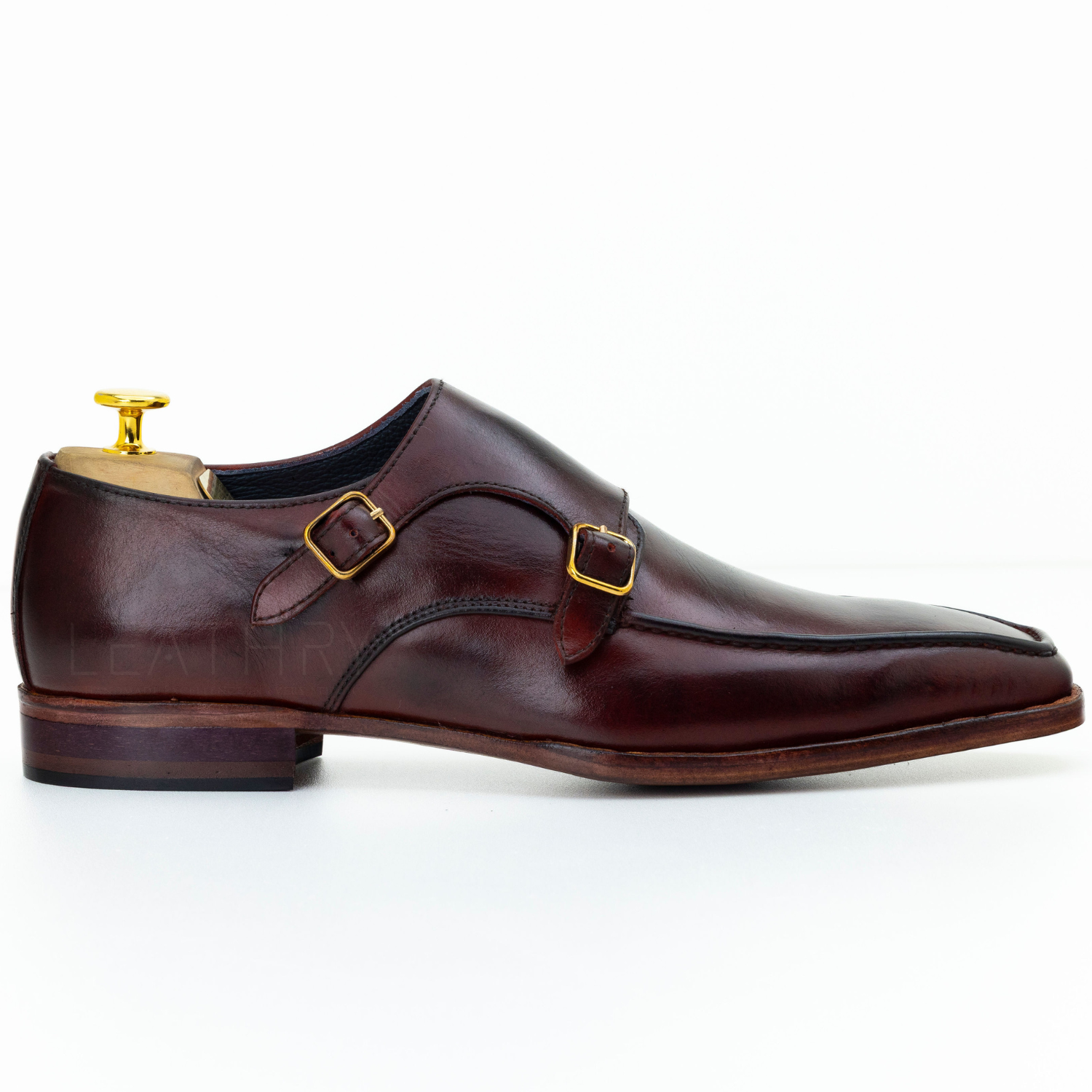 Brown leather shoe with gold buckles on a white background