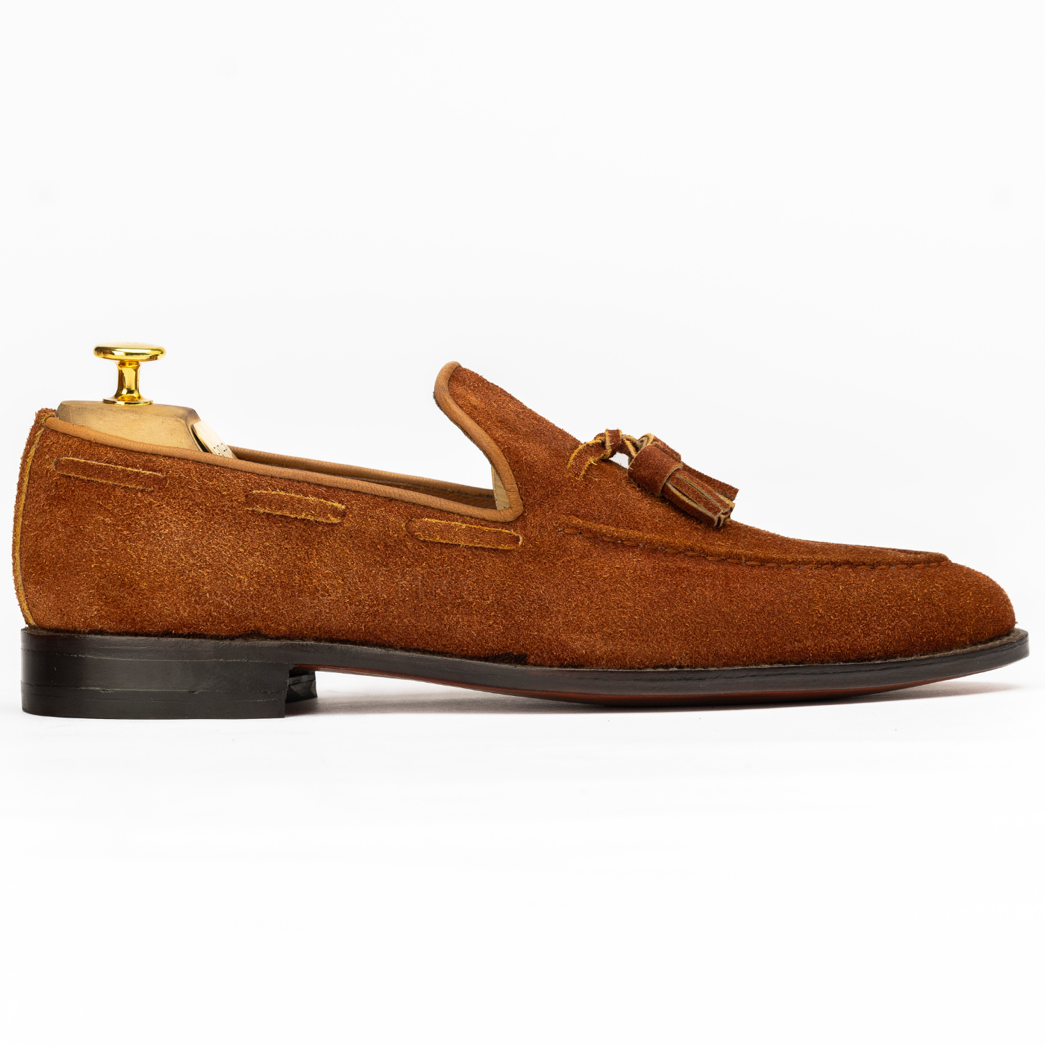Brown suede loafer with a tassel on a white background