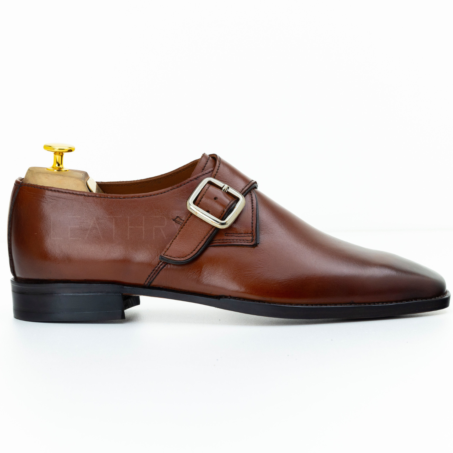 Brown leather dress shoe with gold buckle on a white background