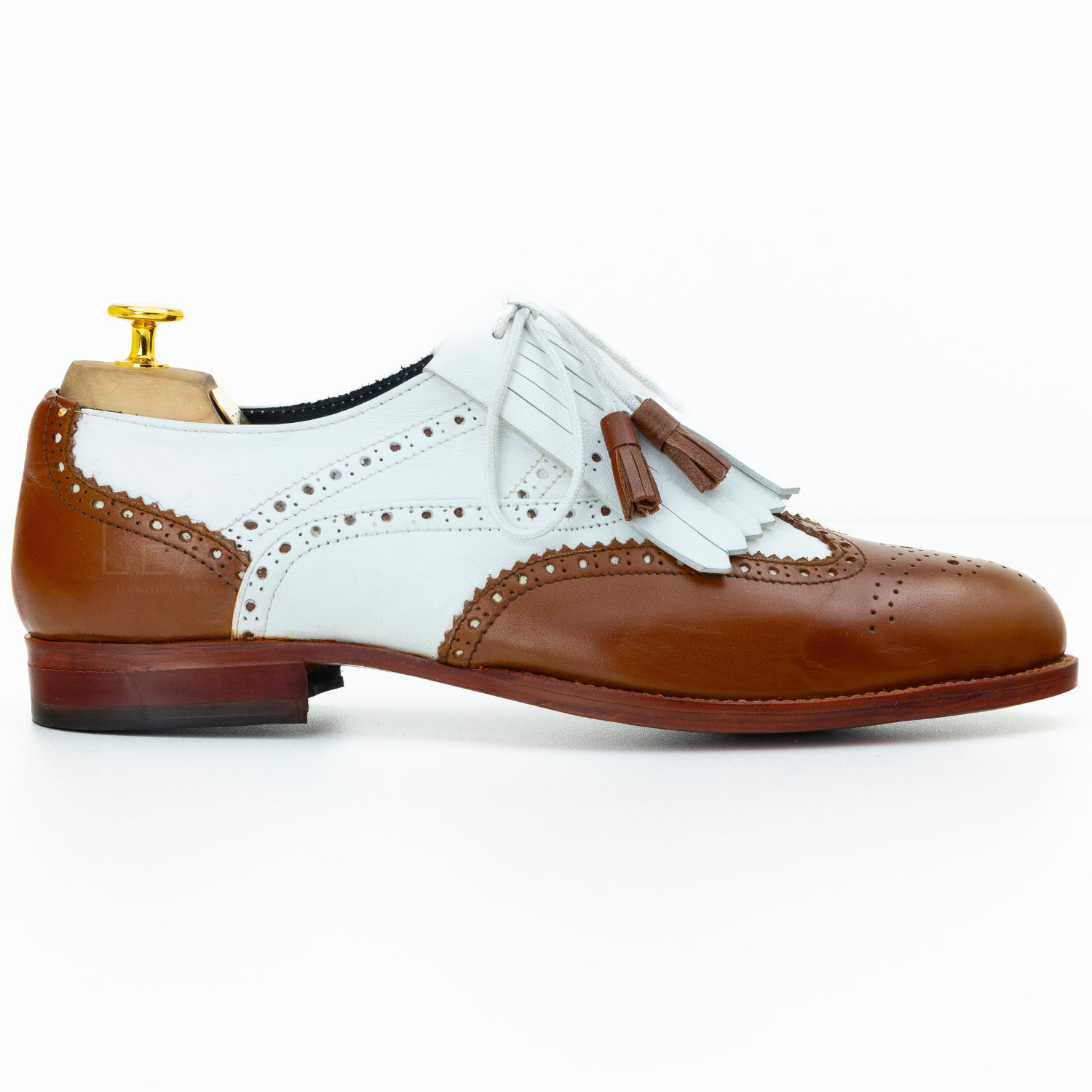Brown and white leather shoe with tassel on a white background