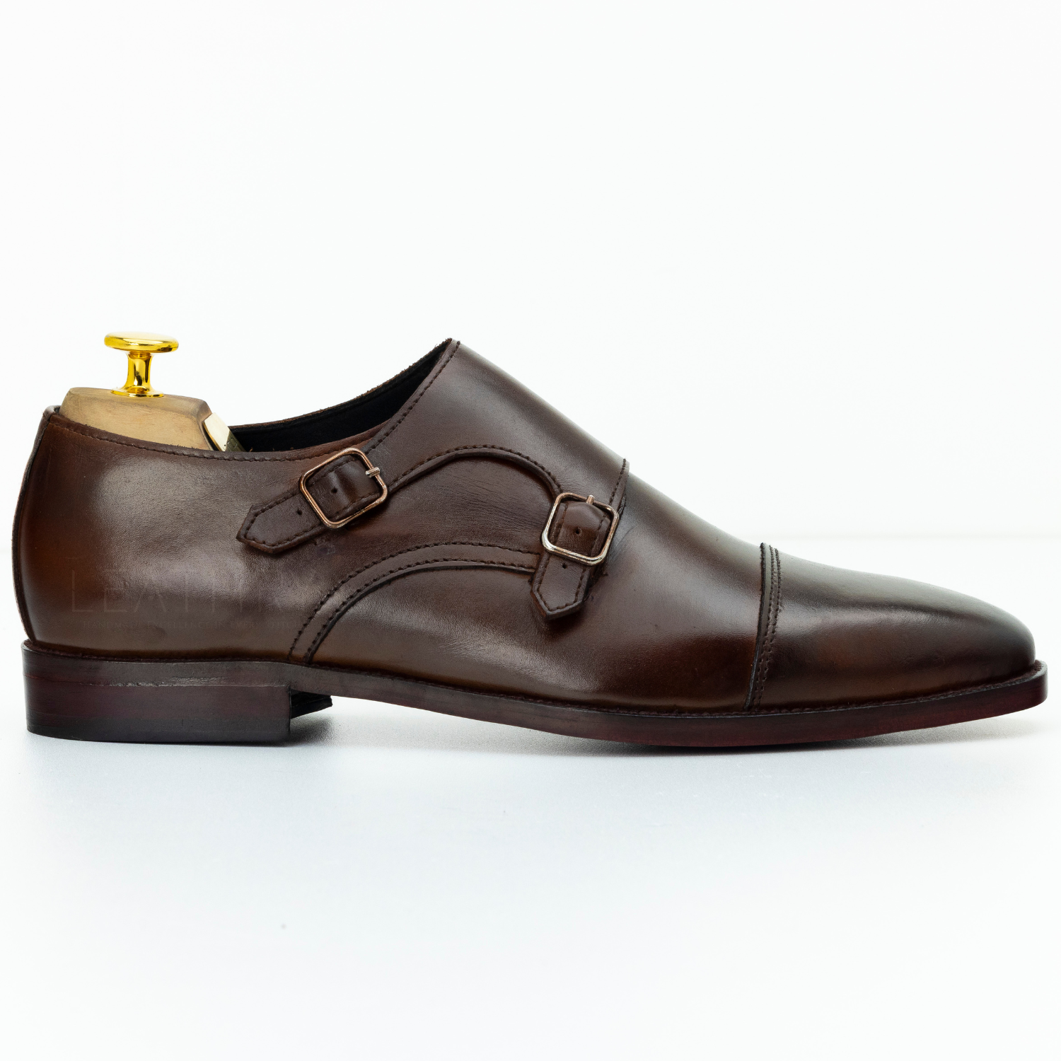 Brown leather shoe with gold buckle on a white background