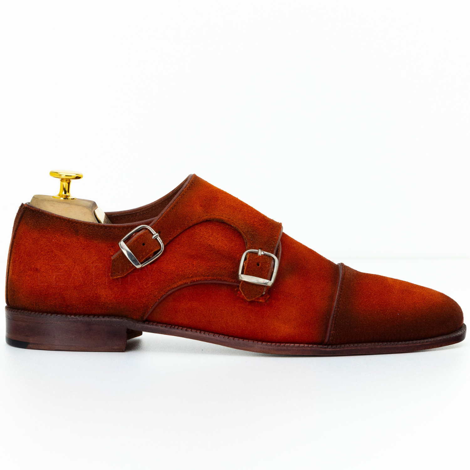 Brown suede monk strap shoe with a gold buckle on a white background