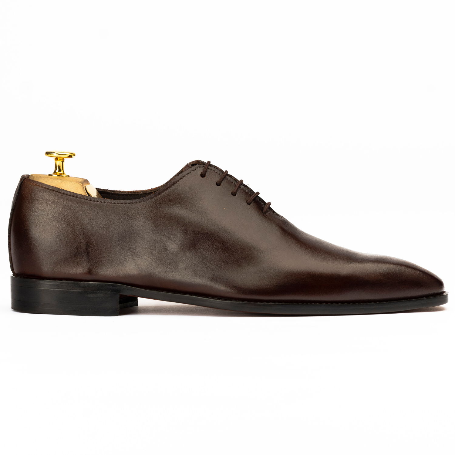 Brown leather dress shoe with a gold tip on a white background