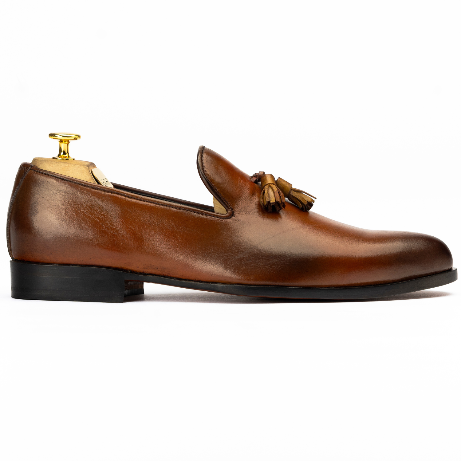 Brown leather loafer with tassel on a white background