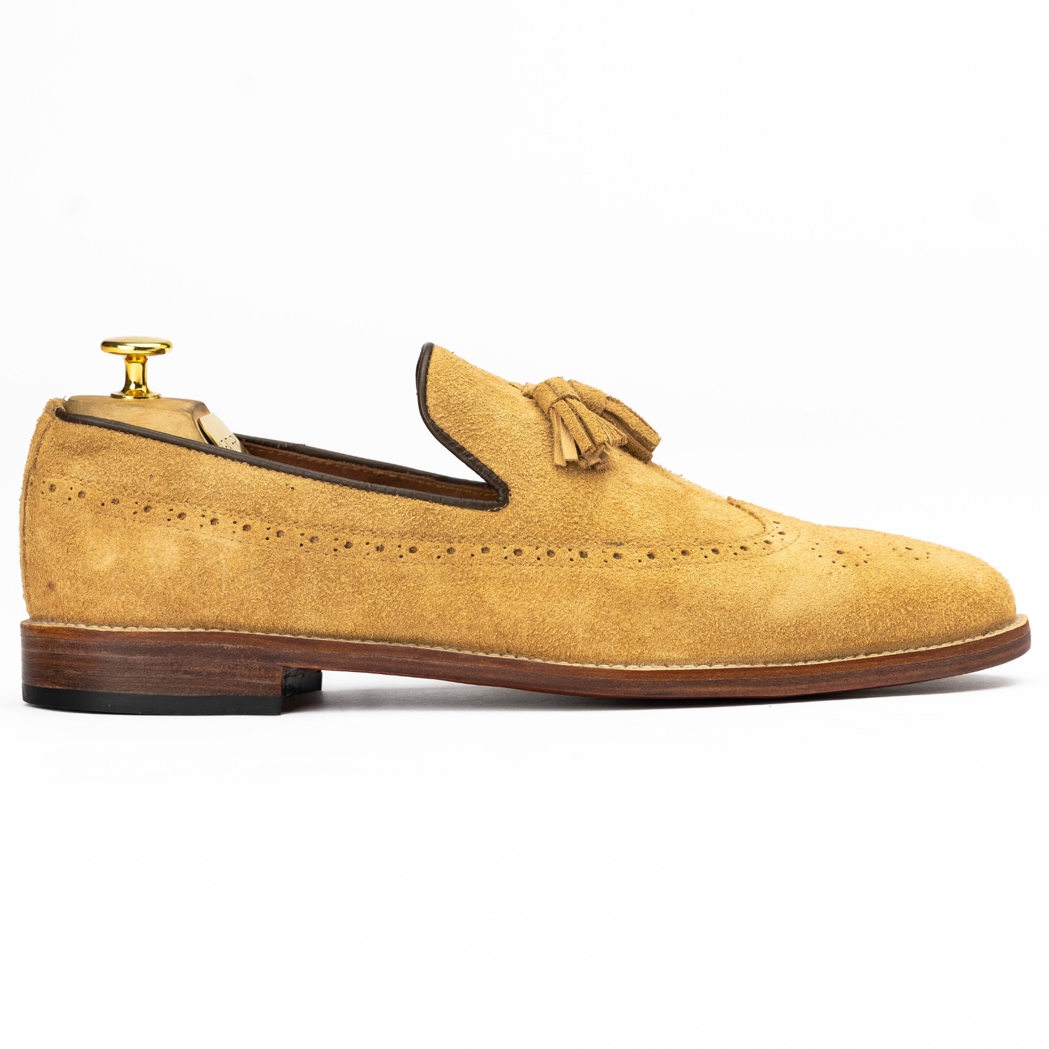 Tan suede loafer with a tassel on a white background