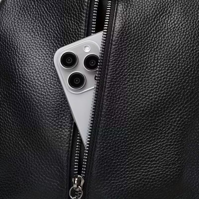 Close-up of a black leather bag with a zipper, featuring a phone with a camera module.