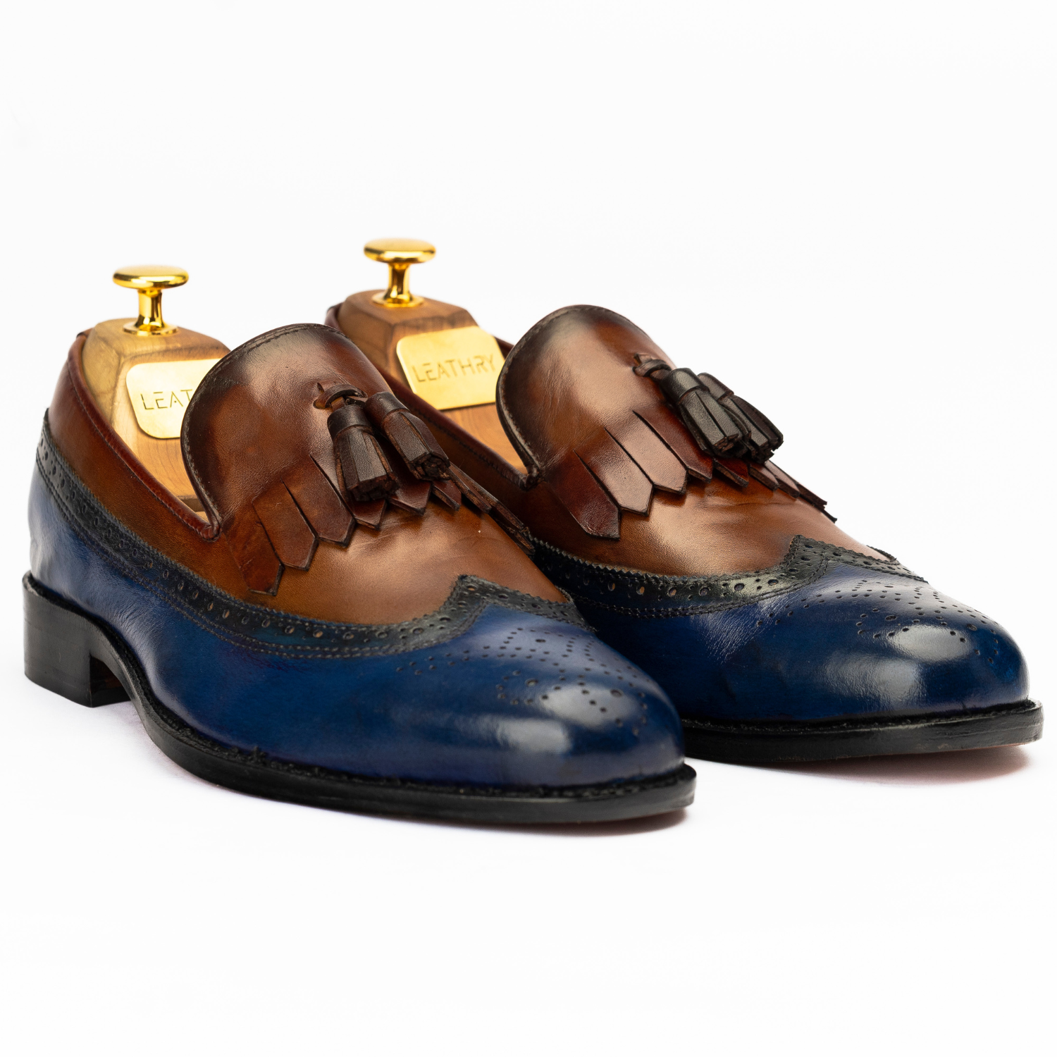 Pair of brown and blue leather shoes with tassels on a white background