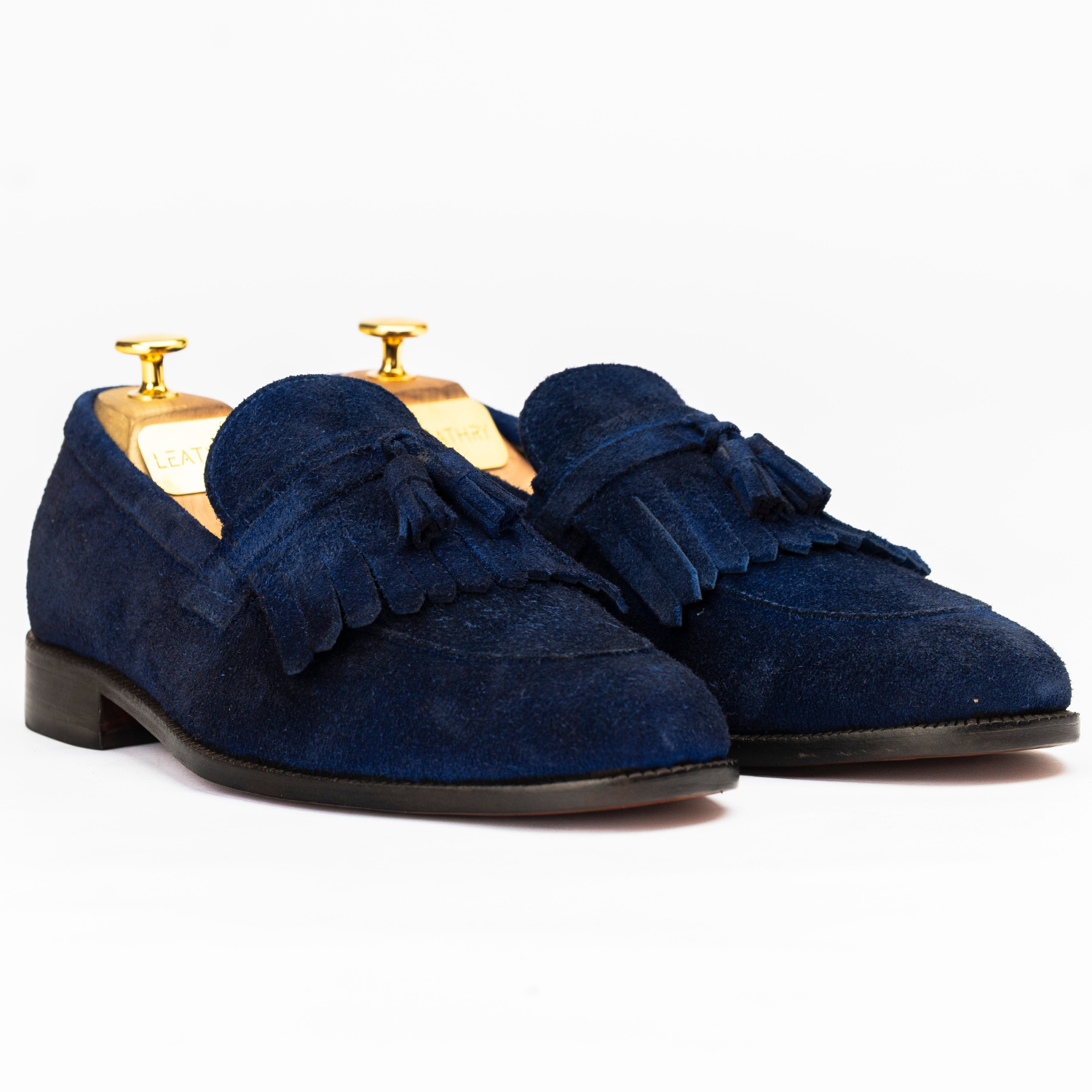Pair of blue suede loafers with tassels on a white background