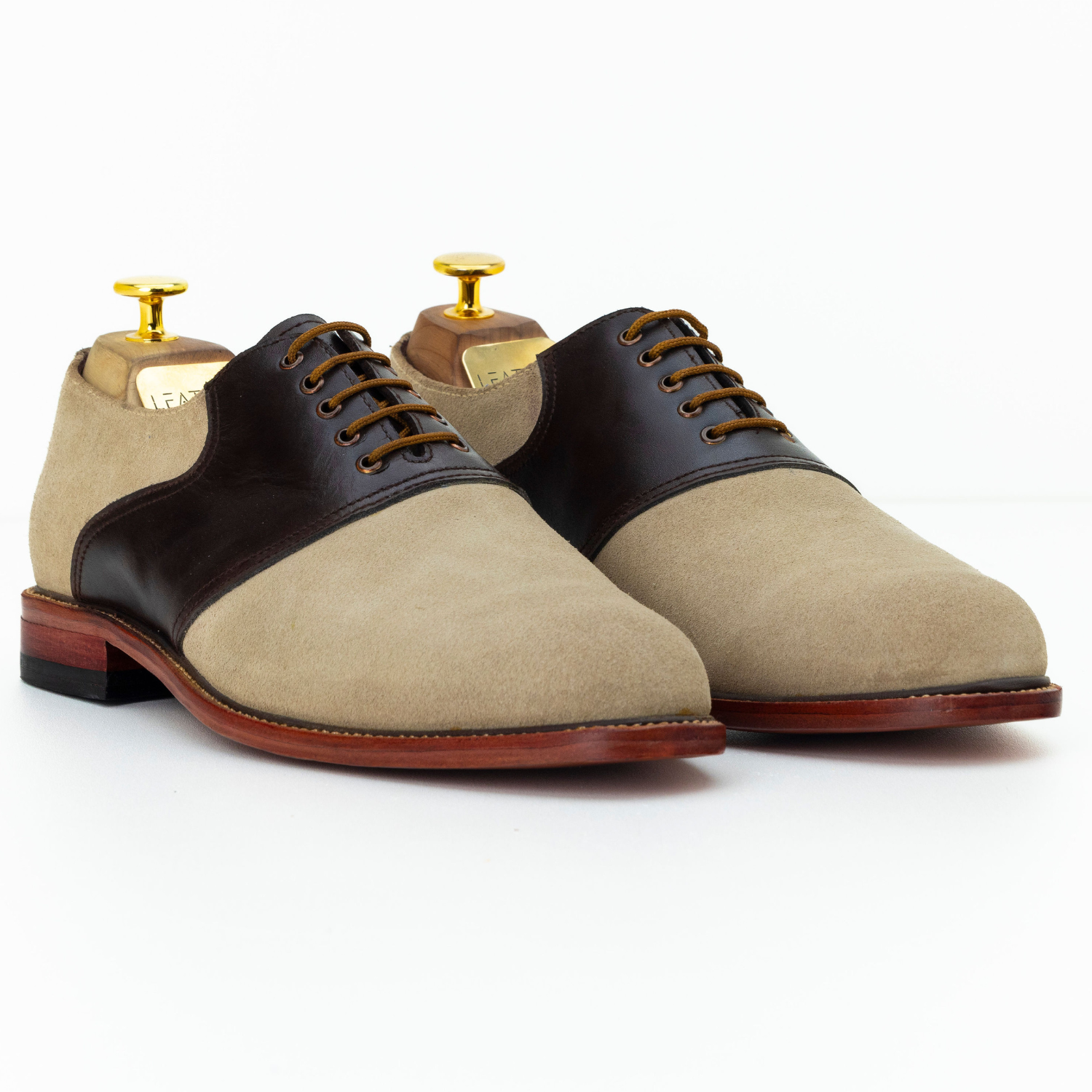 Pair of two-tone dress shoes with beige and black color scheme on a white background