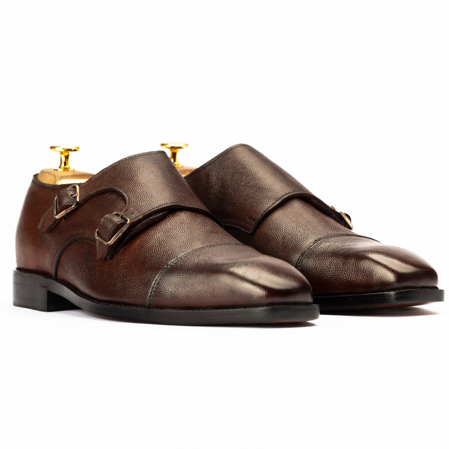 Pair of brown leather shoes with gold buckles on a white background