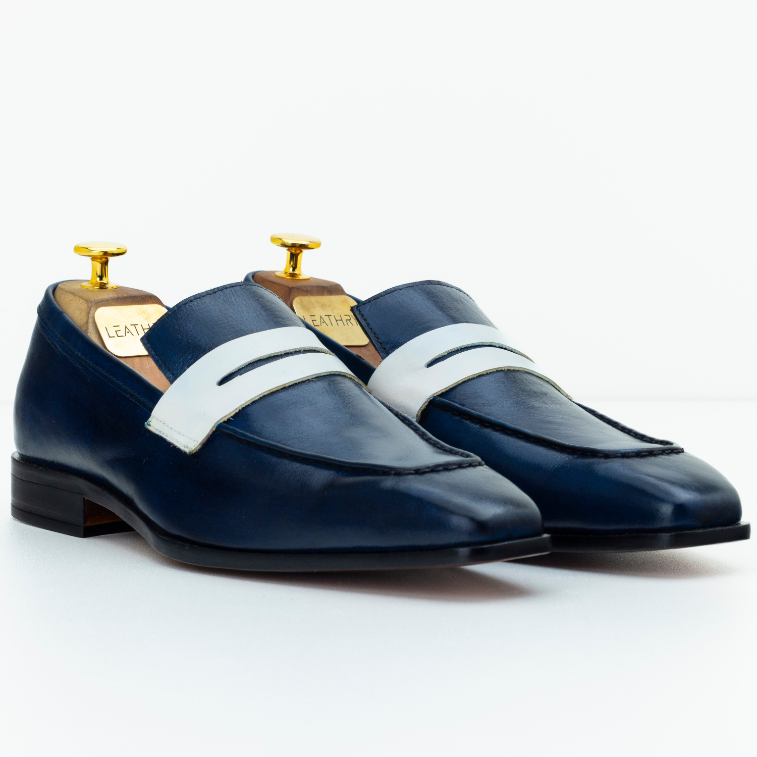 Pair of navy loafers with white straps on a white background