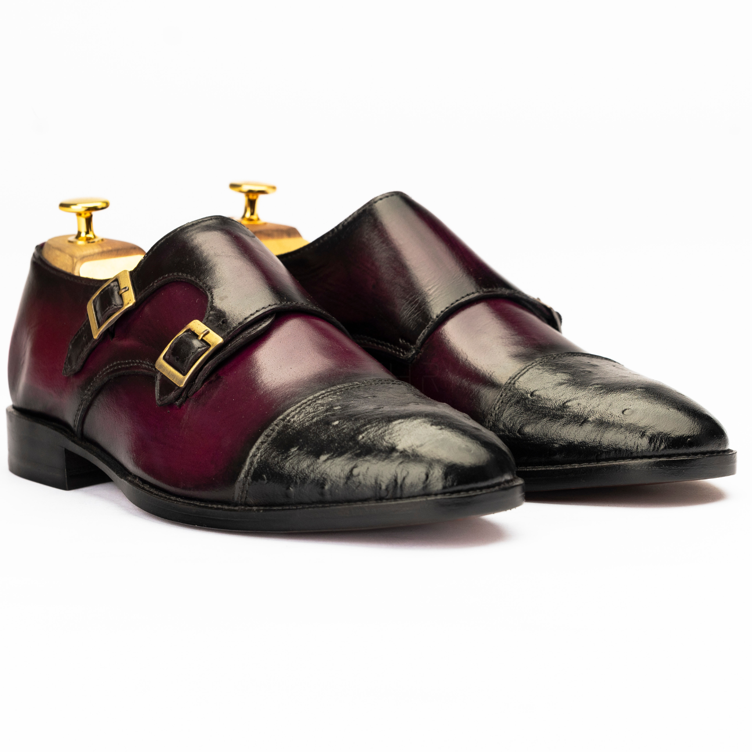 Pair of maroon and black dress shoes with gold buckles on a white background