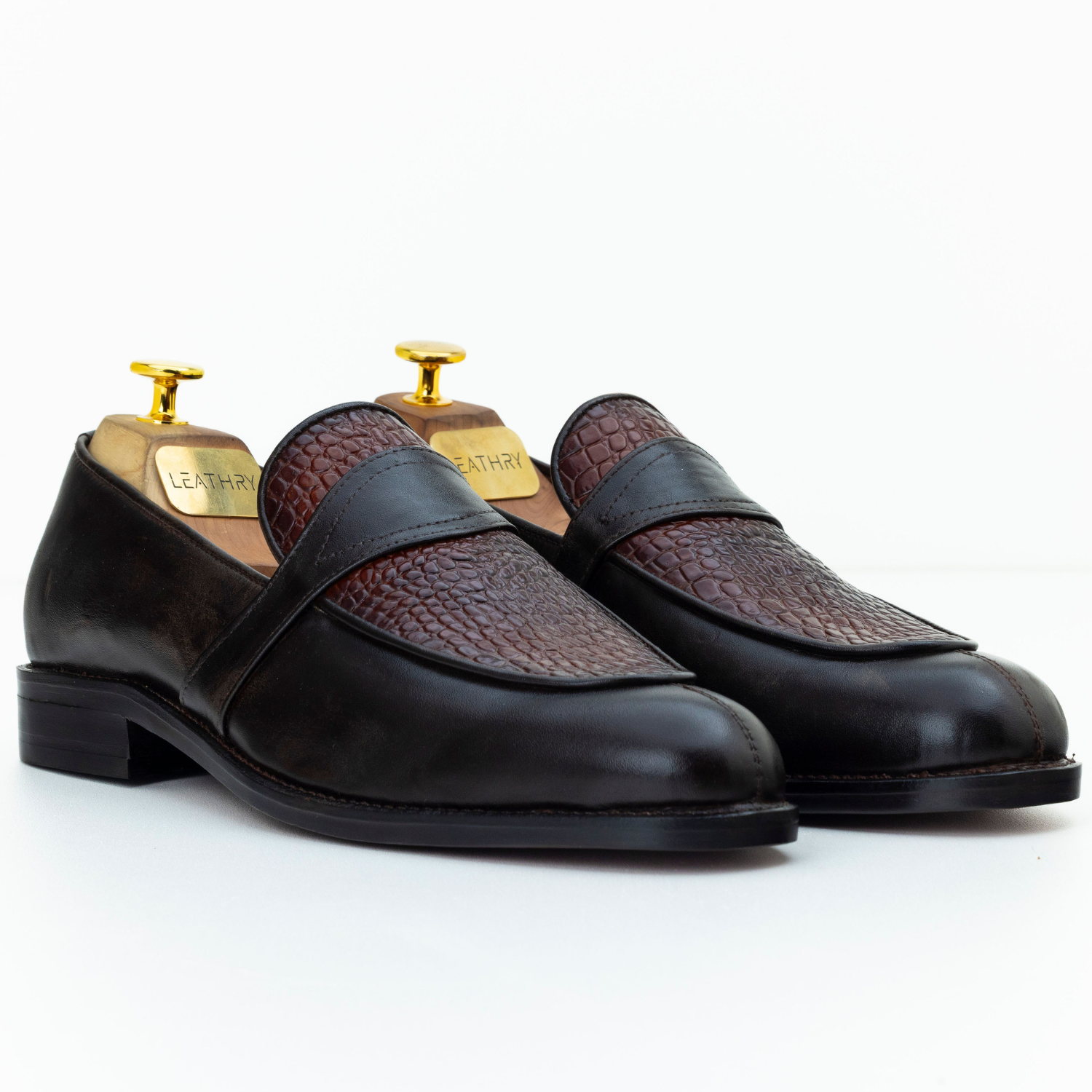 Pair of black and brown leather loafers on a white background