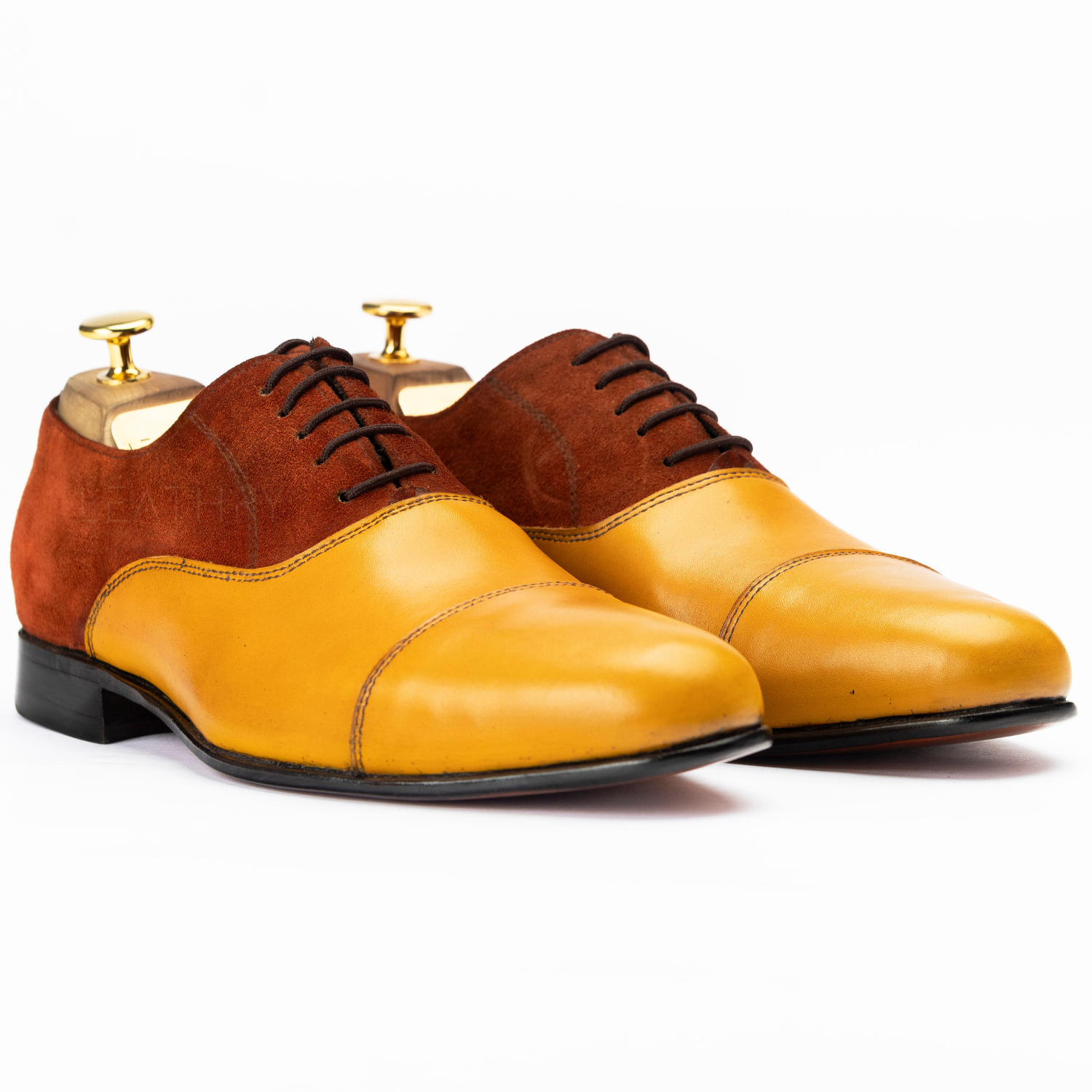 Pair of brown and yellow leather dress shoes on a white background