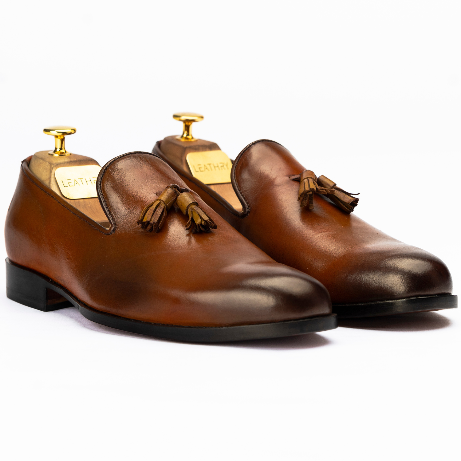 Pair of brown leather loafers with tassels on a white background