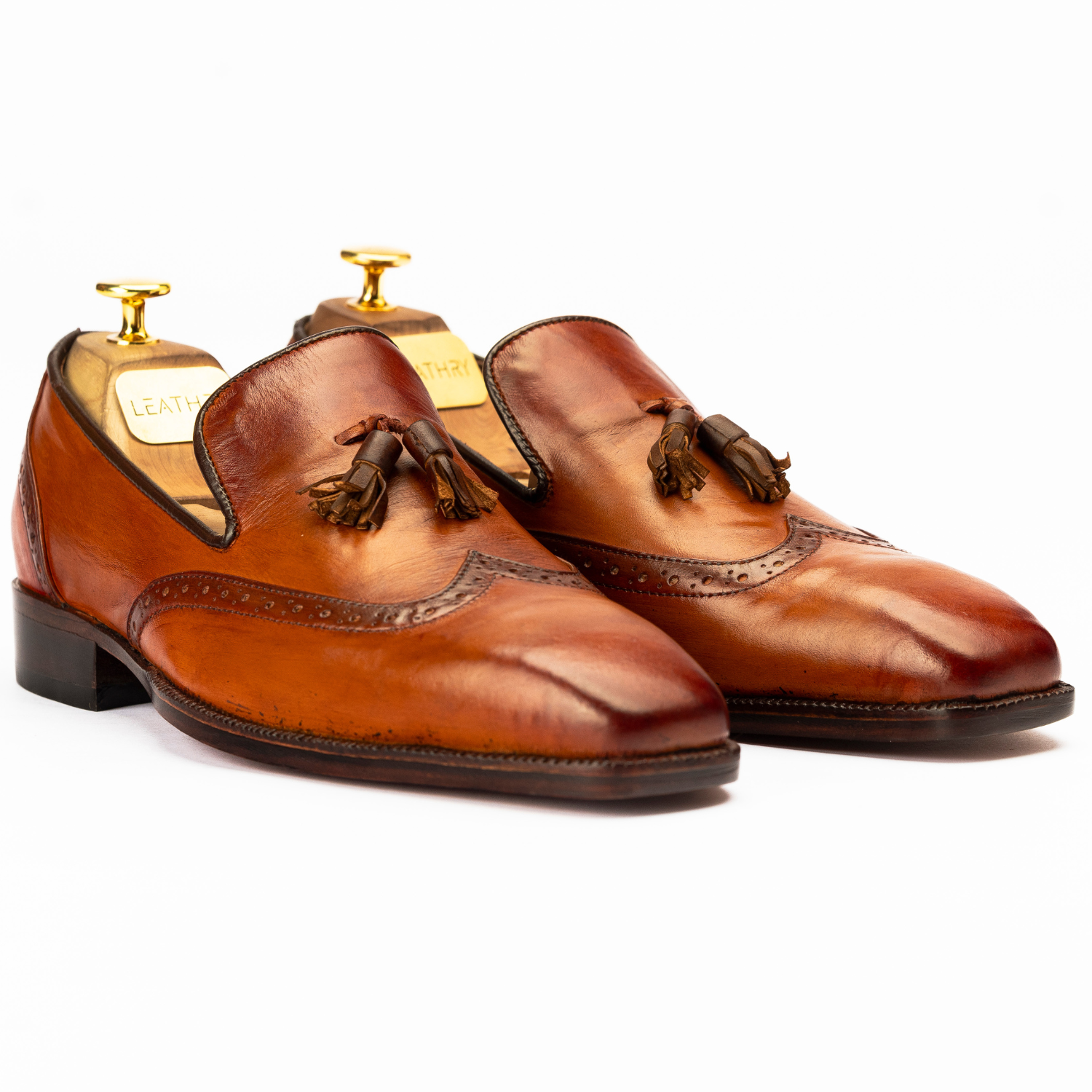 Pair of brown leather shoes with tassels on a white background
