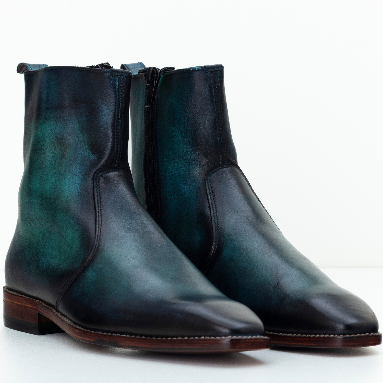 Pair of black and green leather boots on a white background