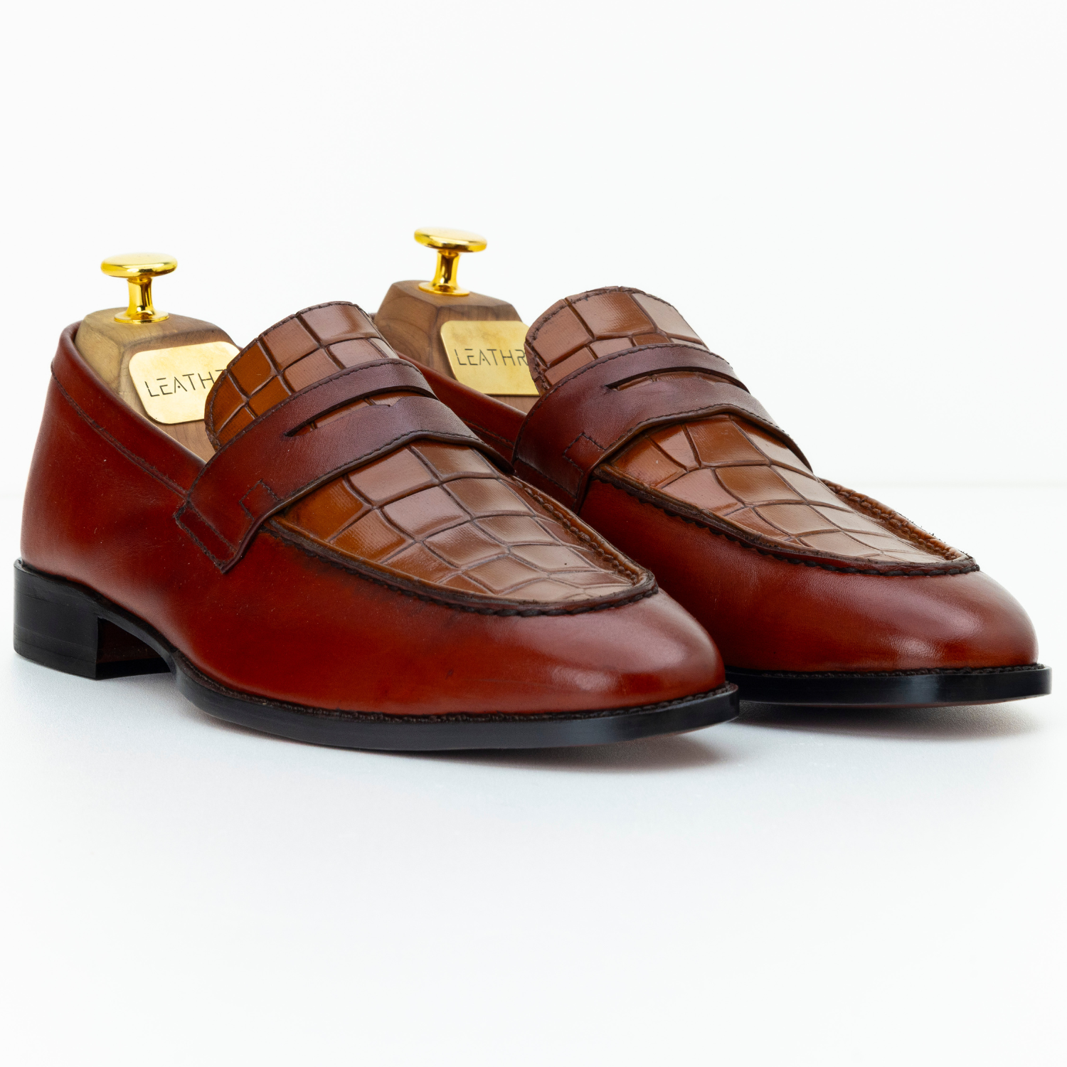 Pair of brown leather loafers with a textured pattern on a white background