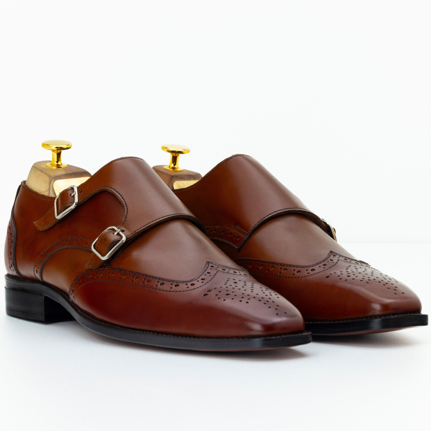 Brown leather shoes with gold buckles on a white background