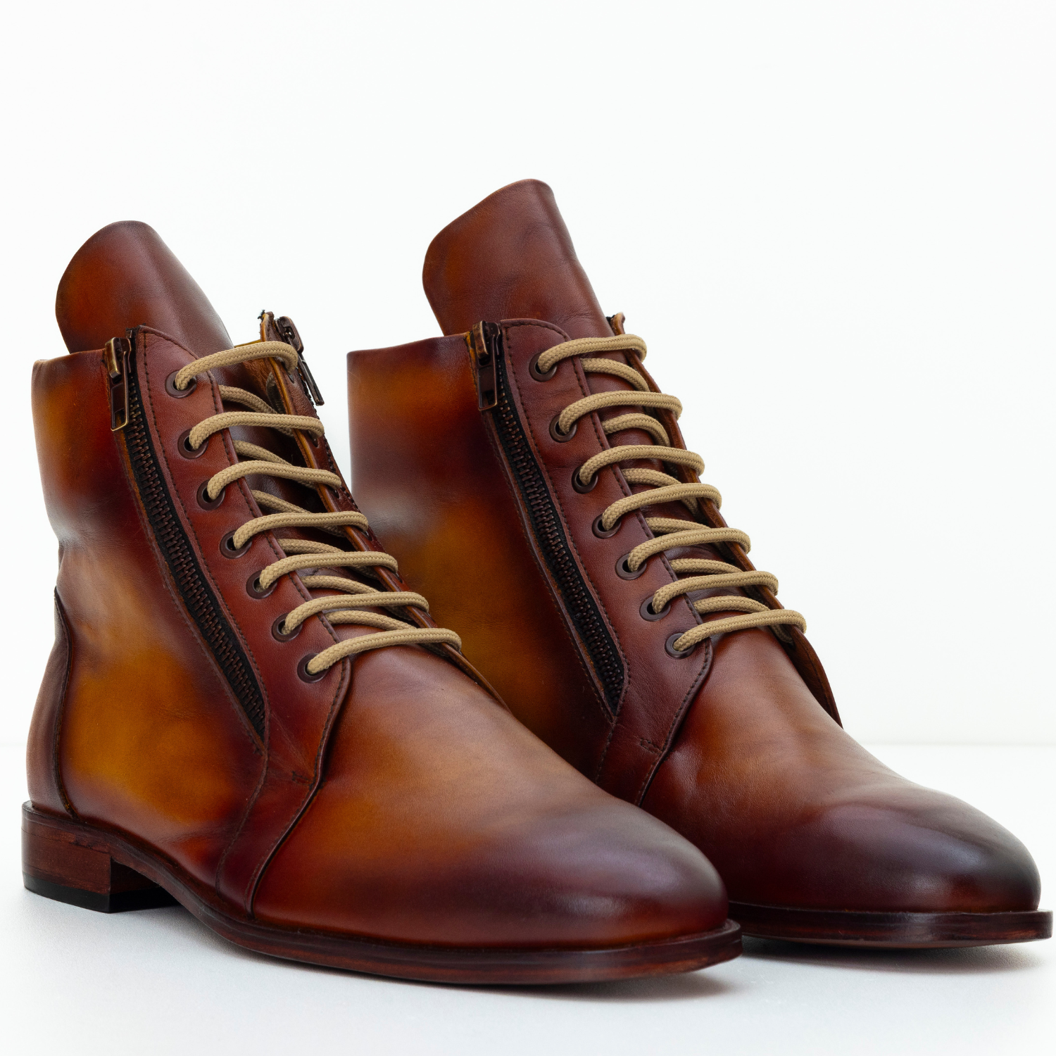 Pair of brown leather boots with tan laces on a white background