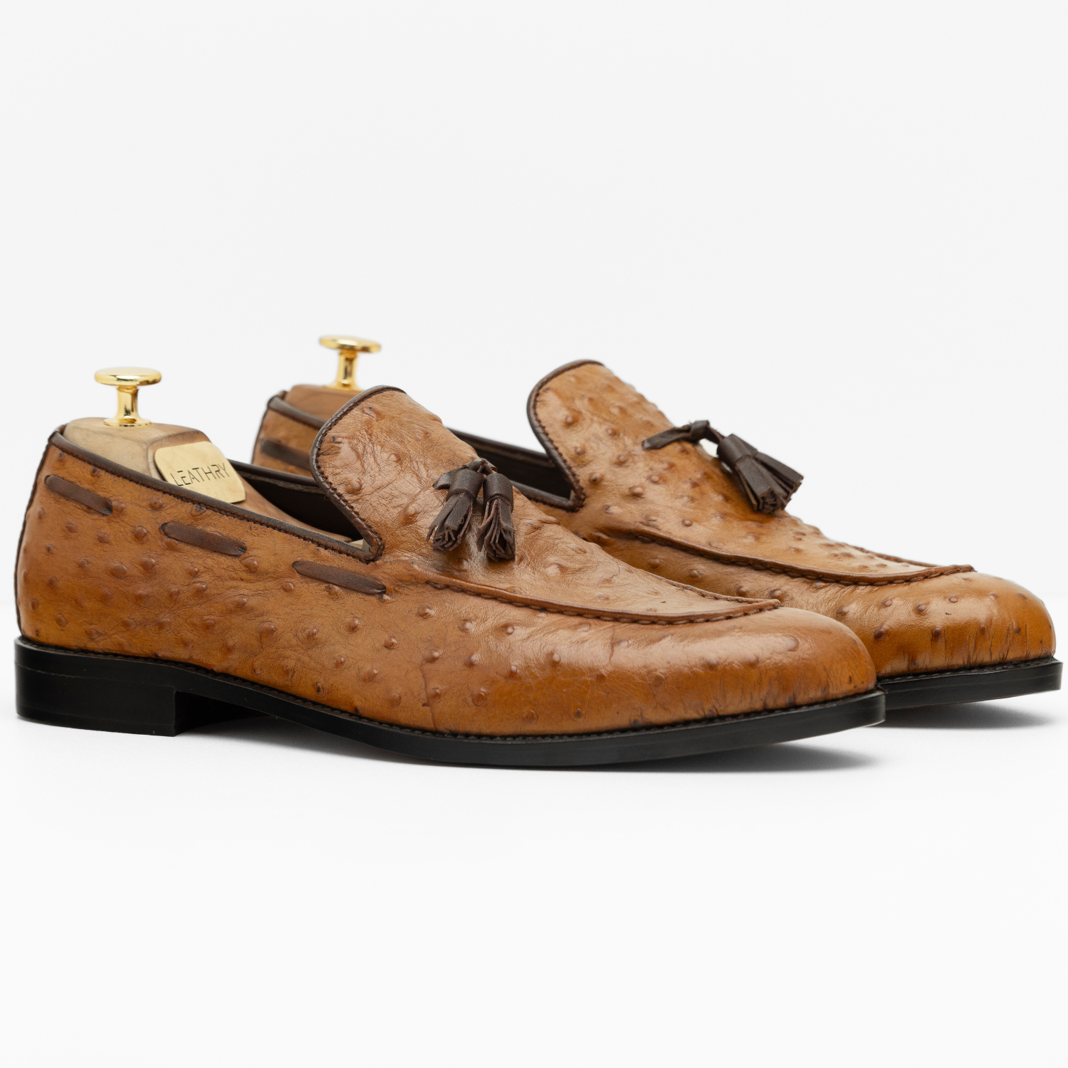 Brown leather loafers with tassels on a white background