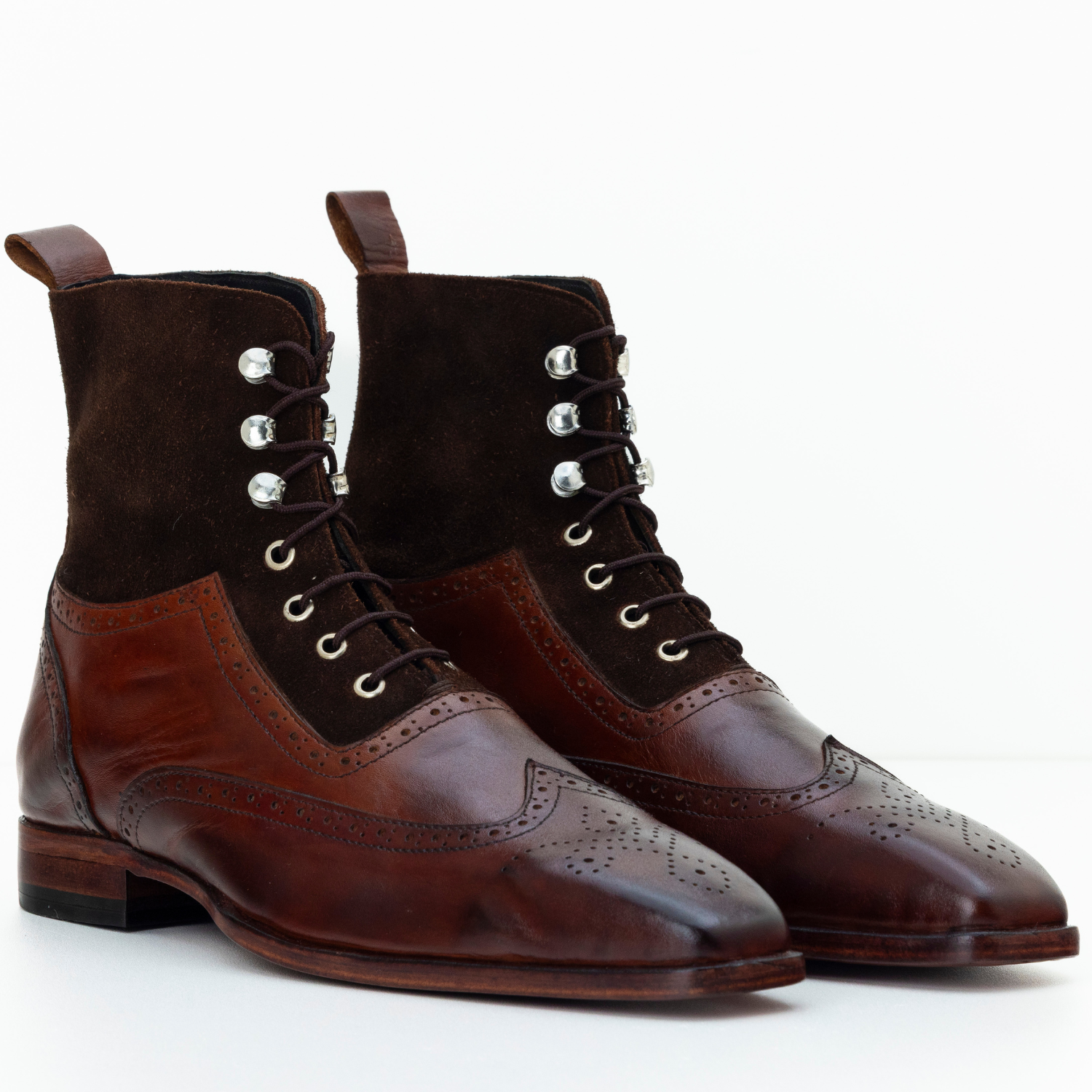 Pair of brown leather dress boots with brogue detailing on a white background