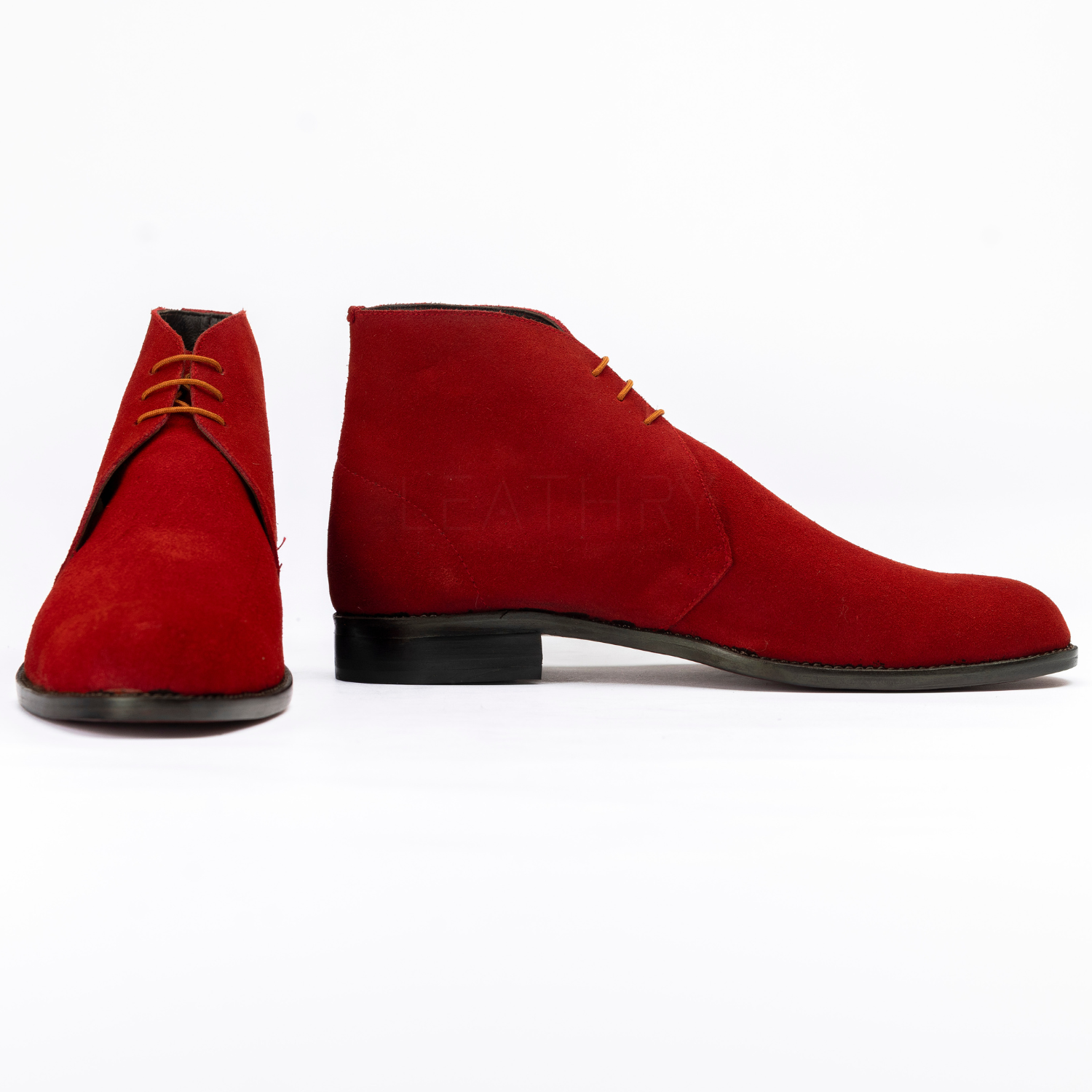 Red suede shoes with black soles on a white background
