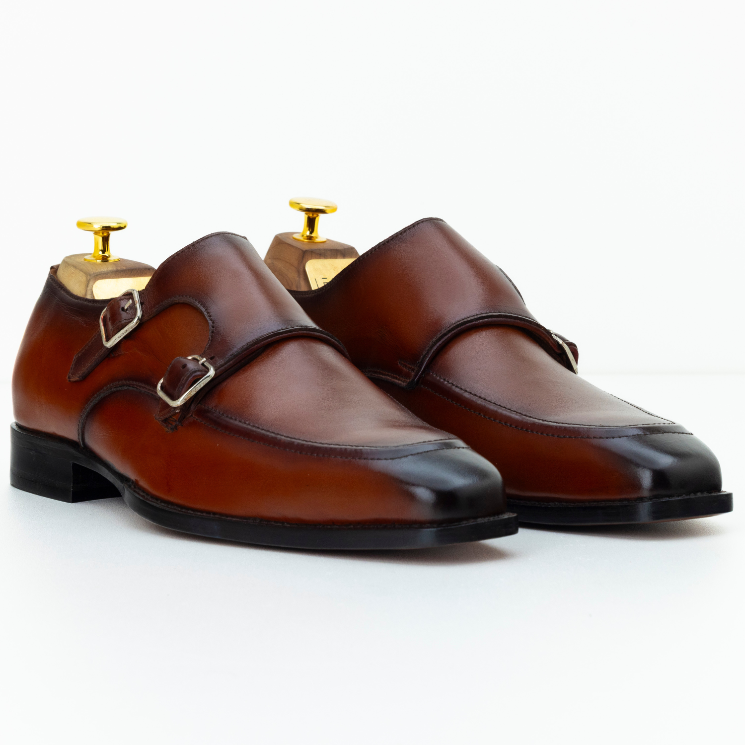 Pair of brown leather shoes with gold buckles on a white background