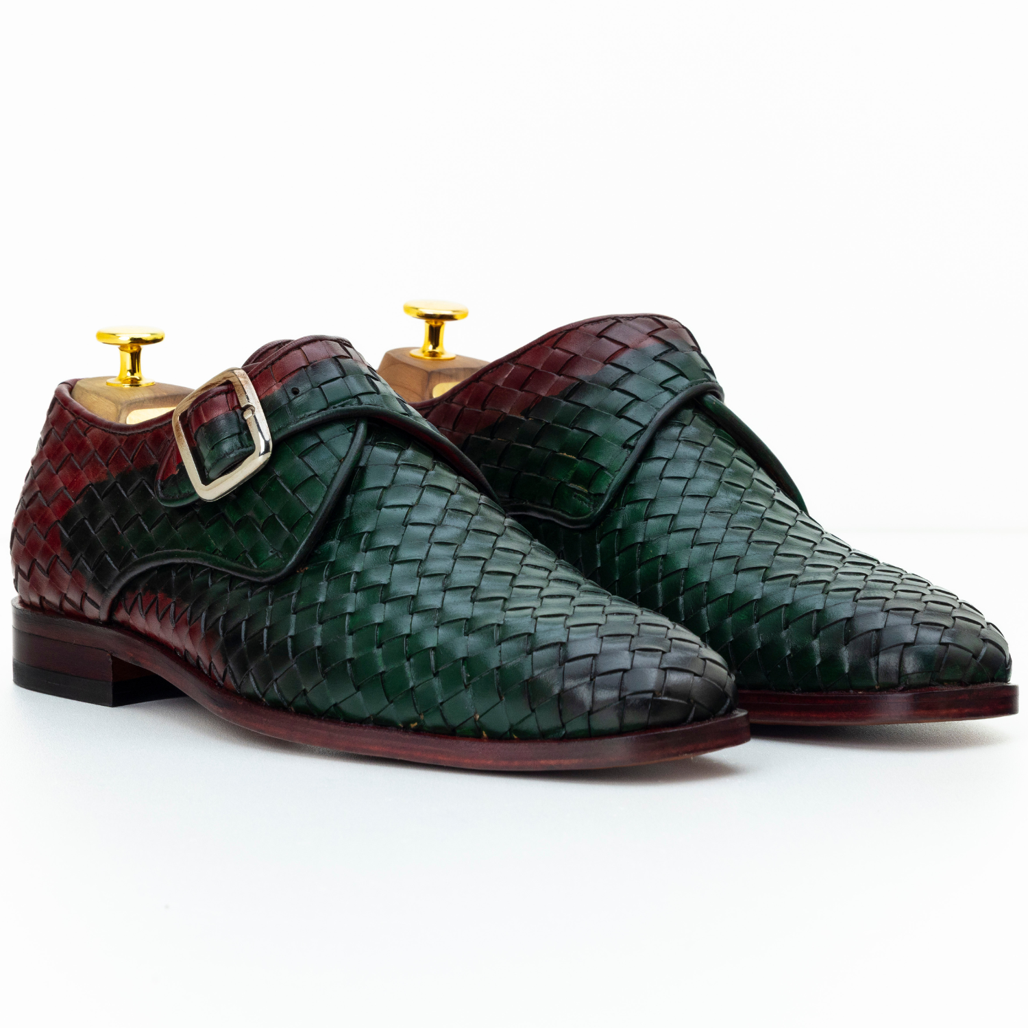 Pair of green and burgundy woven leather shoes with gold buckles on a white background