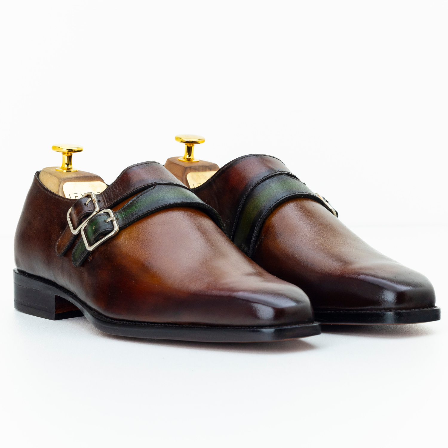 Pair of brown leather shoes with gold buckles on a white background
