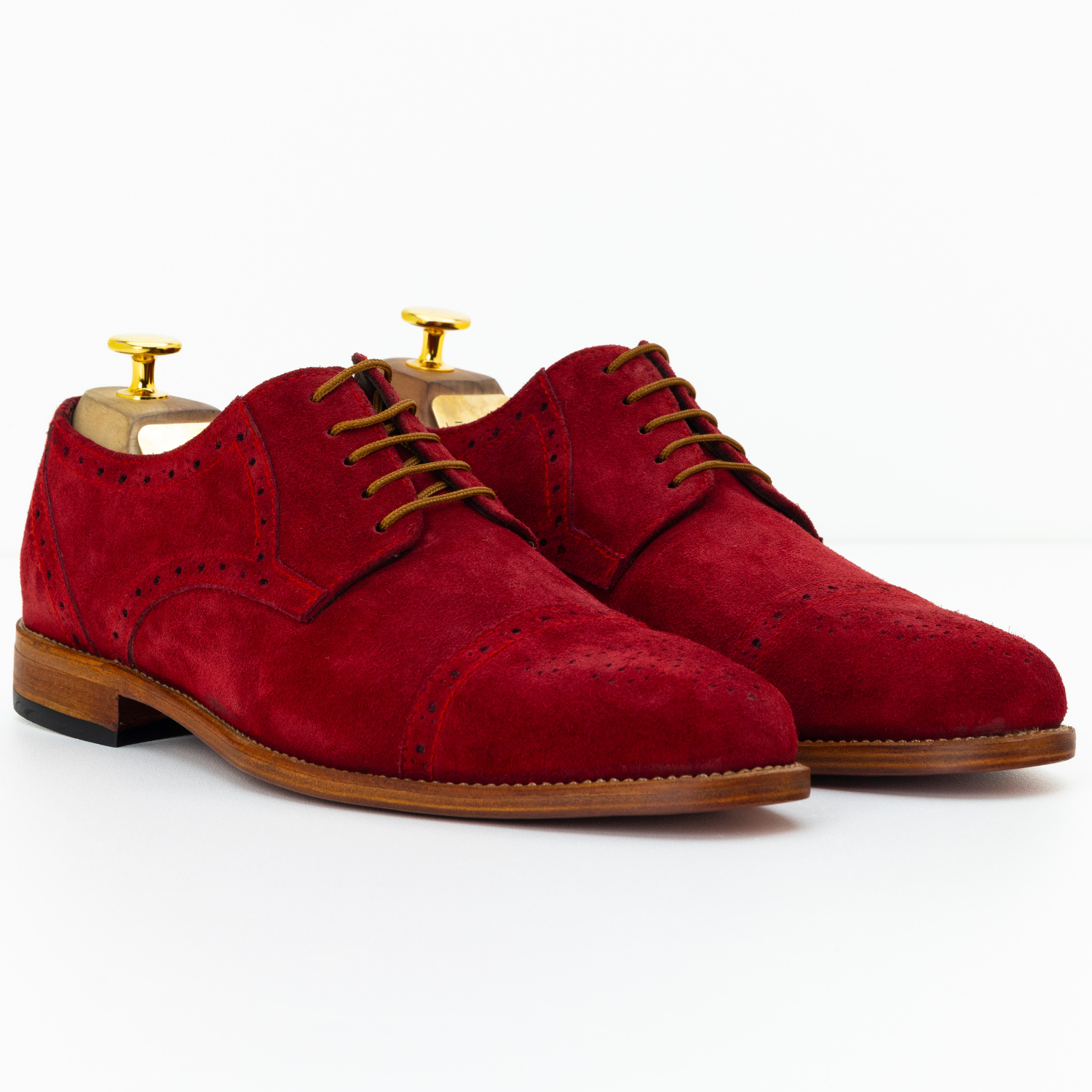 Red suede shoes with brown accents on a white background