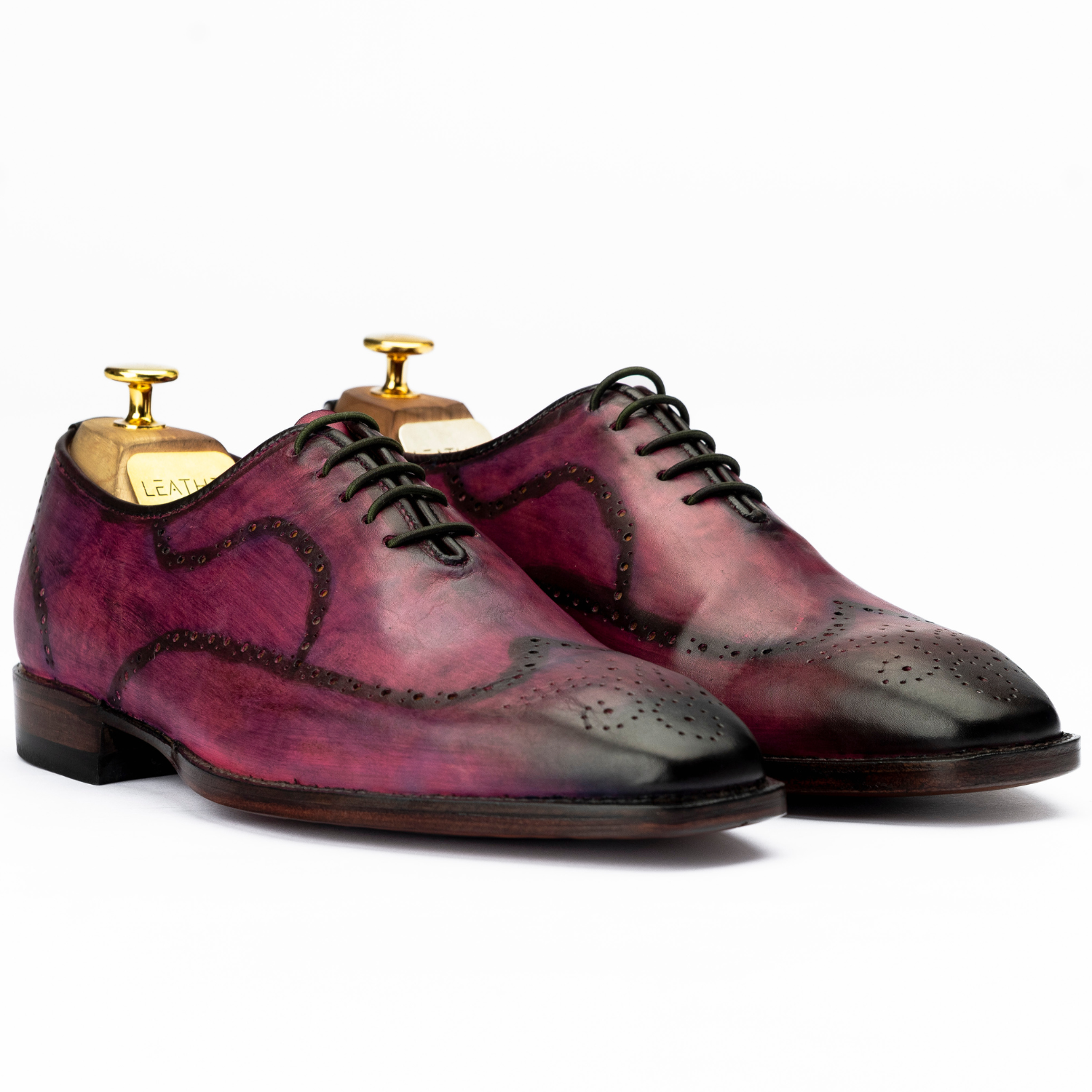 Pair of purple and black leather shoes with gold accents on a white background