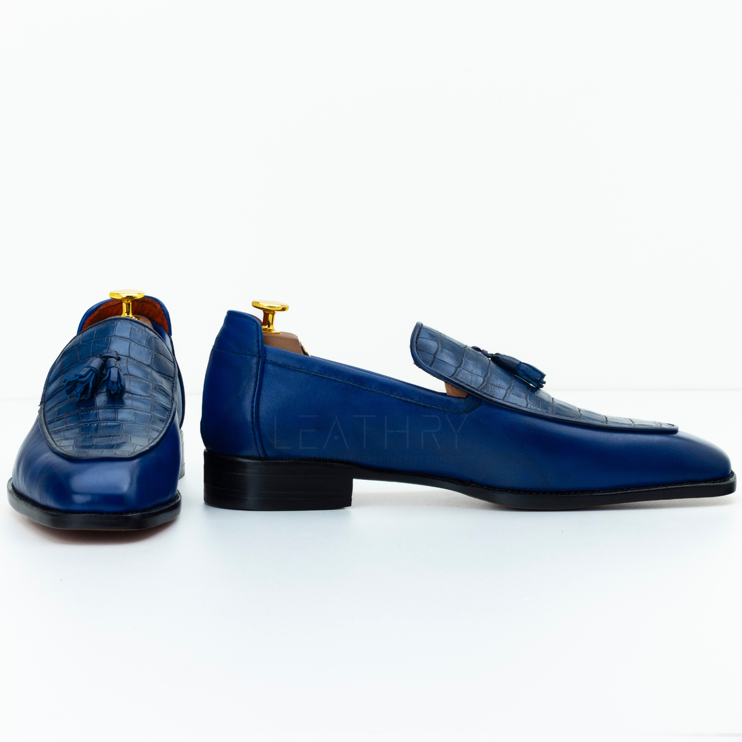 Pair of blue leather loafers with tassels on a white background