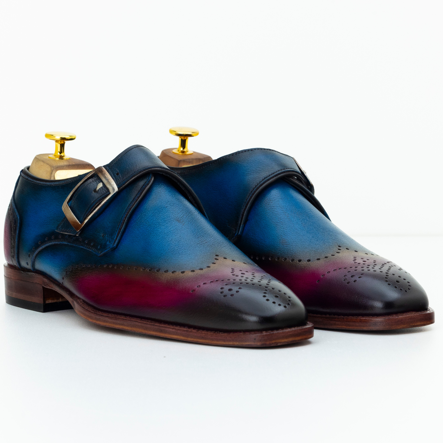 Pair of blue and black leather shoes with gold buckles on a white background