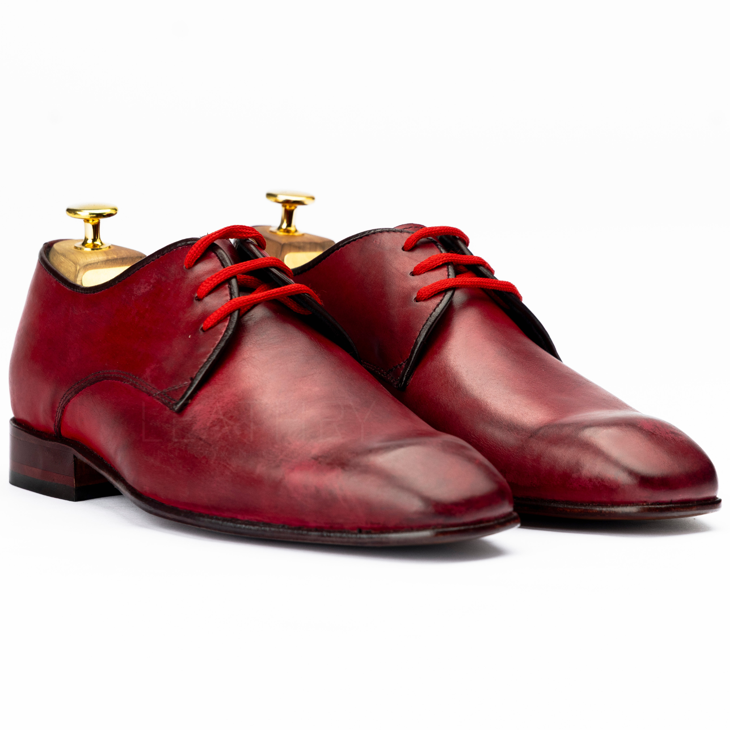 Pair of red leather dress shoes with red laces on a white background